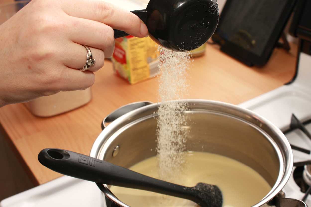 A hand pours sugar into the Pistachio Ice Cream base