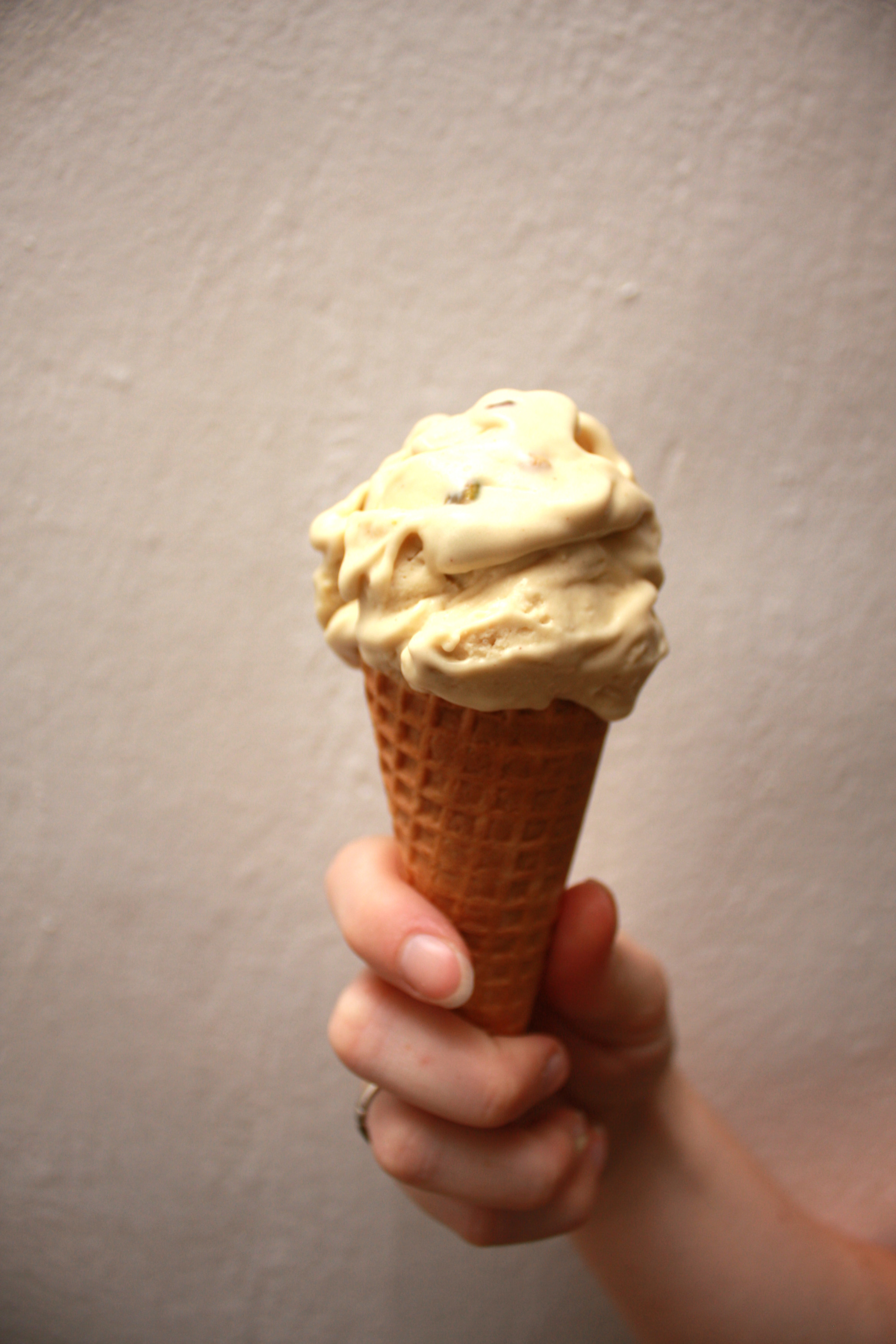 A hand holds a cone with pistachio ice cream