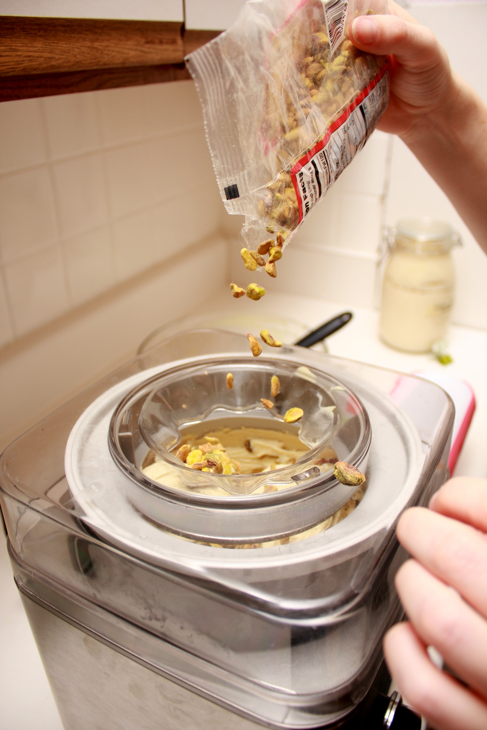 Alyssa pours pistachios into the ice cream maker