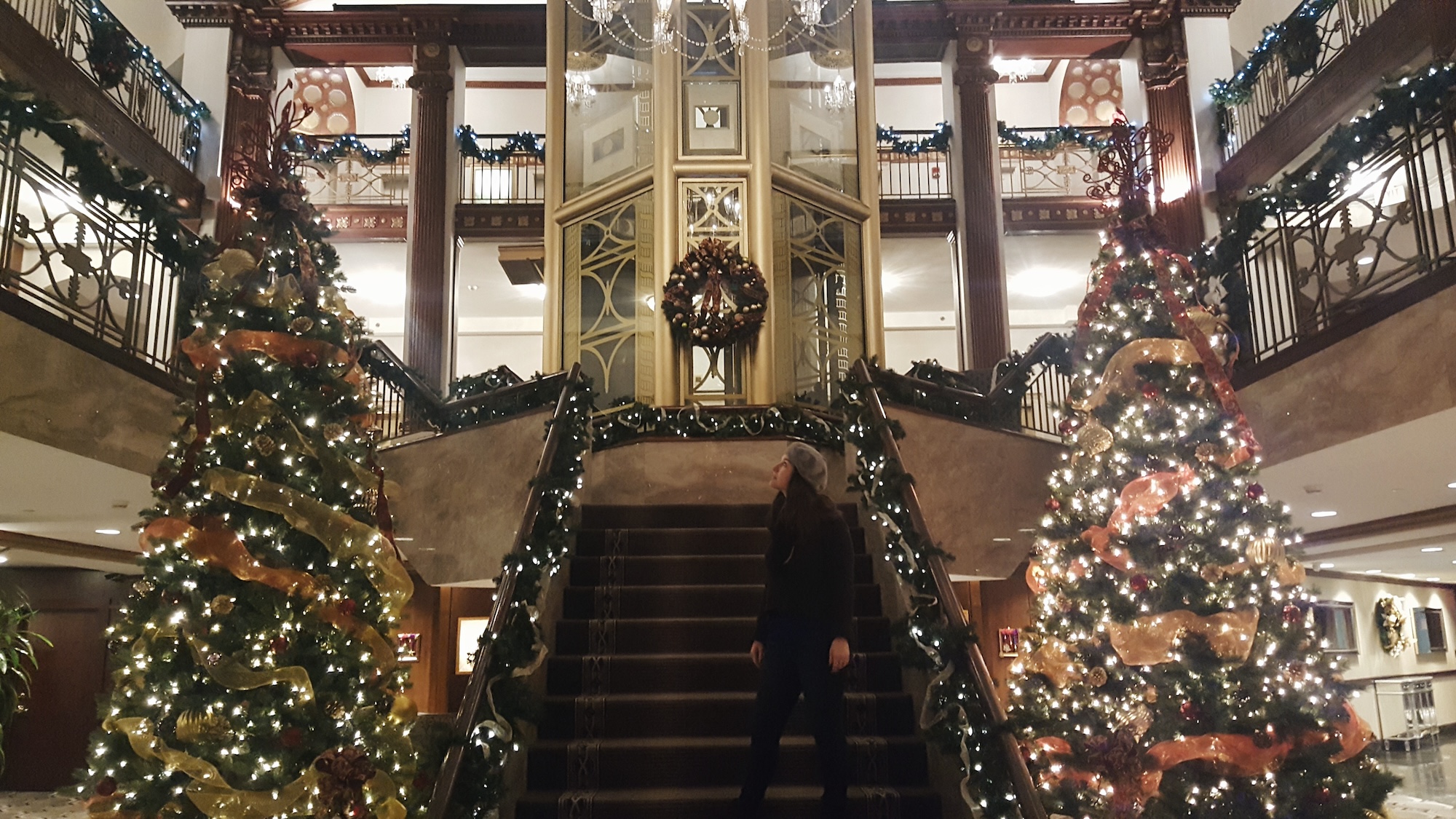 Alyssa in the lobby of the hotel with Christmas trees and lights