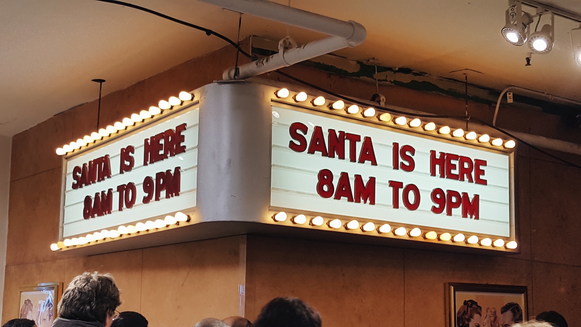 A sign advertising Santa at Macy's