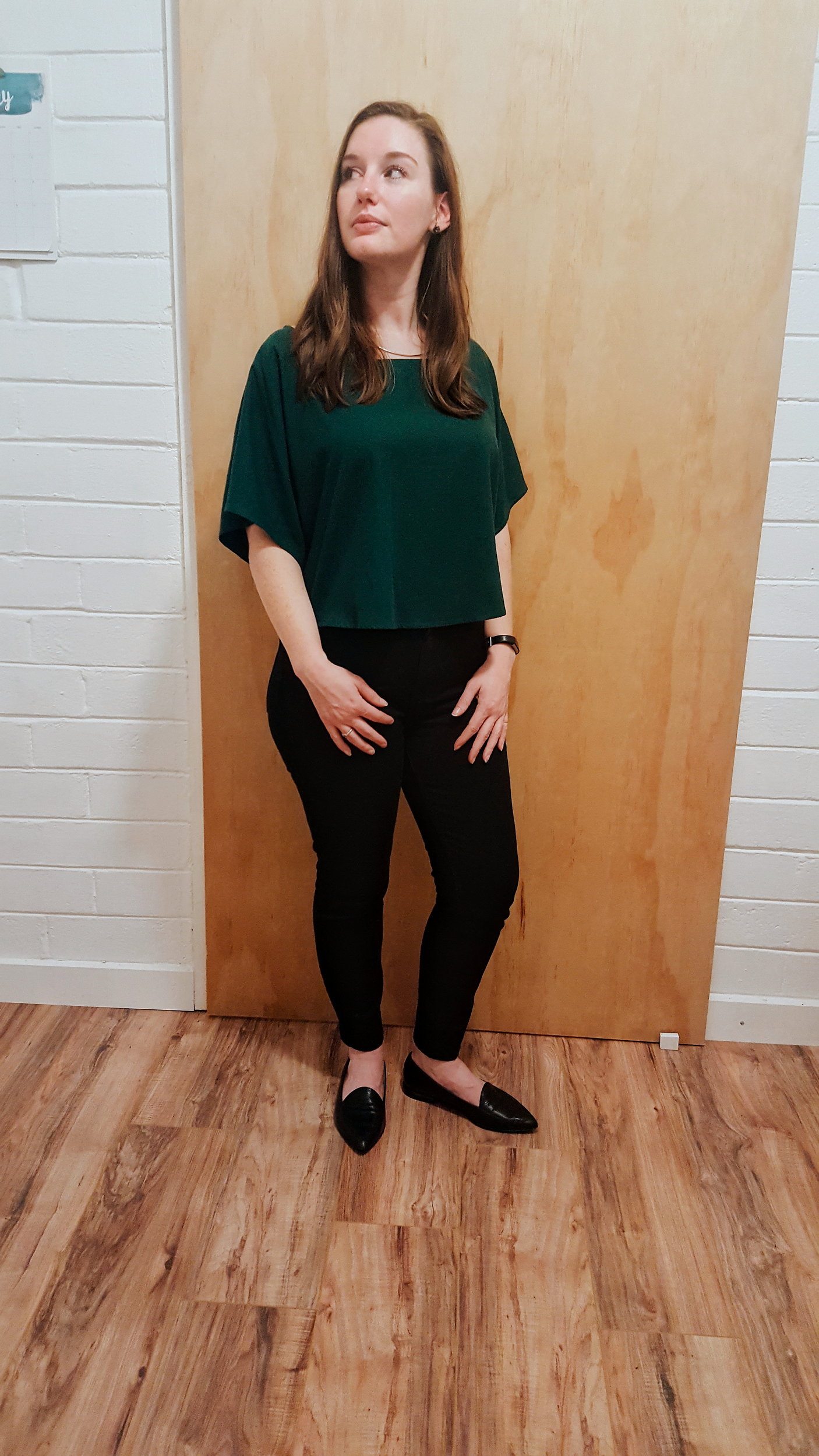 Alyssa wears a green top, black jeans, and black flats in the evening