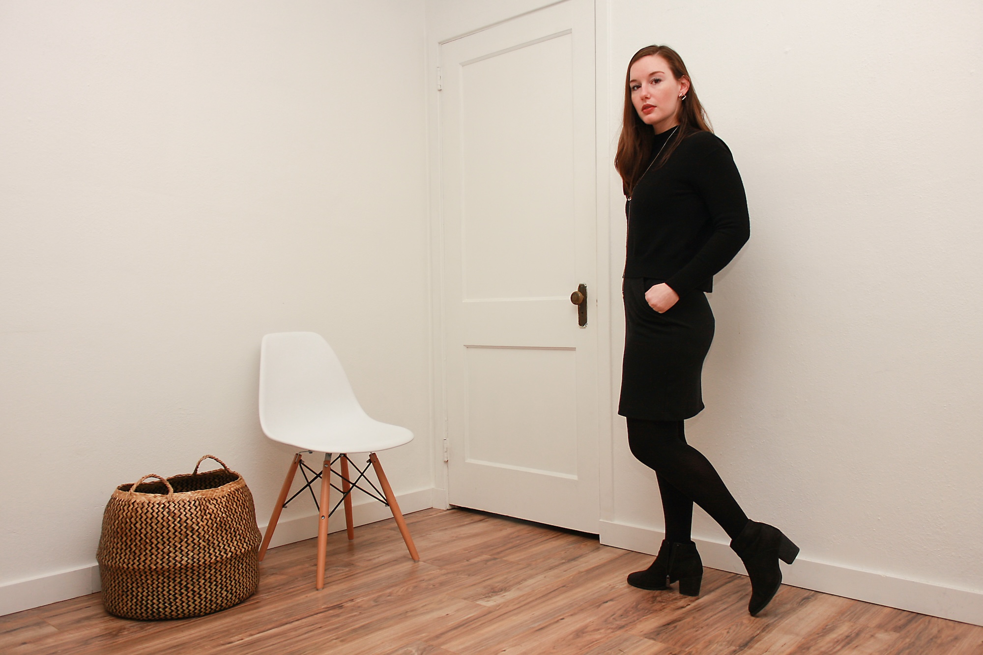 Alyssa wears a black turtleneck sweater over a black dress with tights and boots