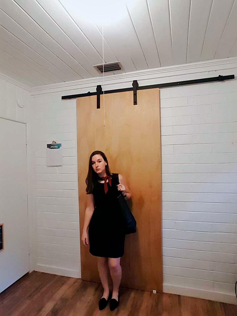 Alyssa wears a black sheath dress with black flats and a rust bandana in the evening