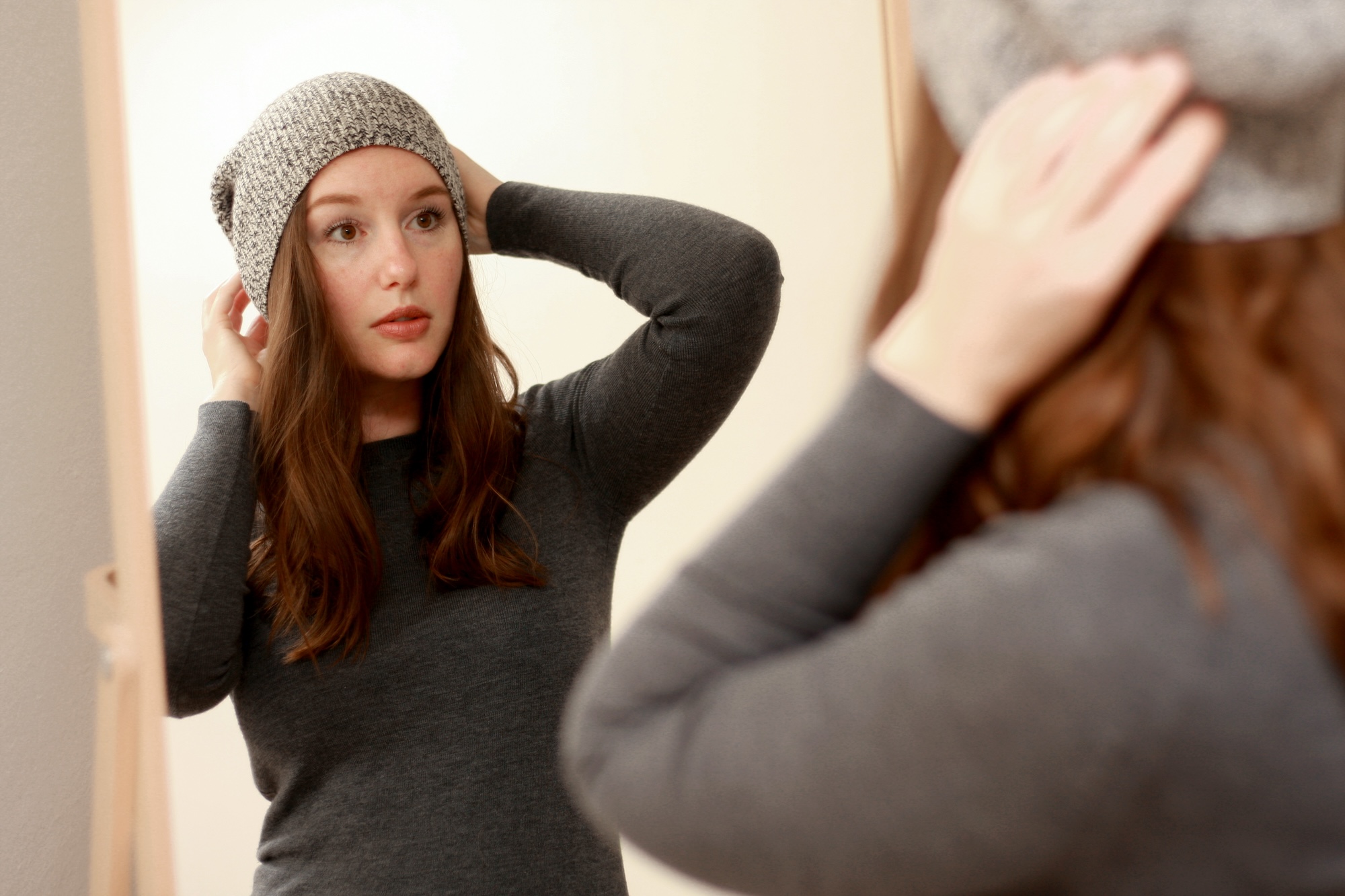 Alyssa adjusts a grey beanie on her head