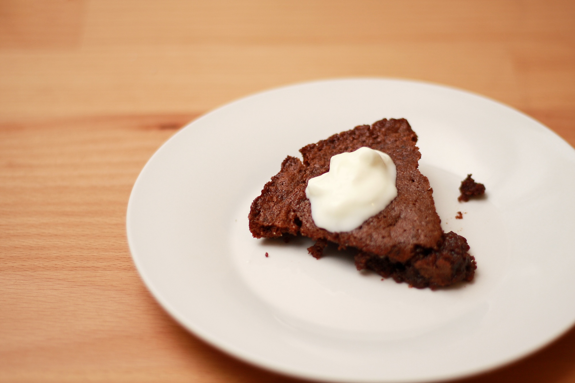 A slice of sticky chocolate cake with whipped cream