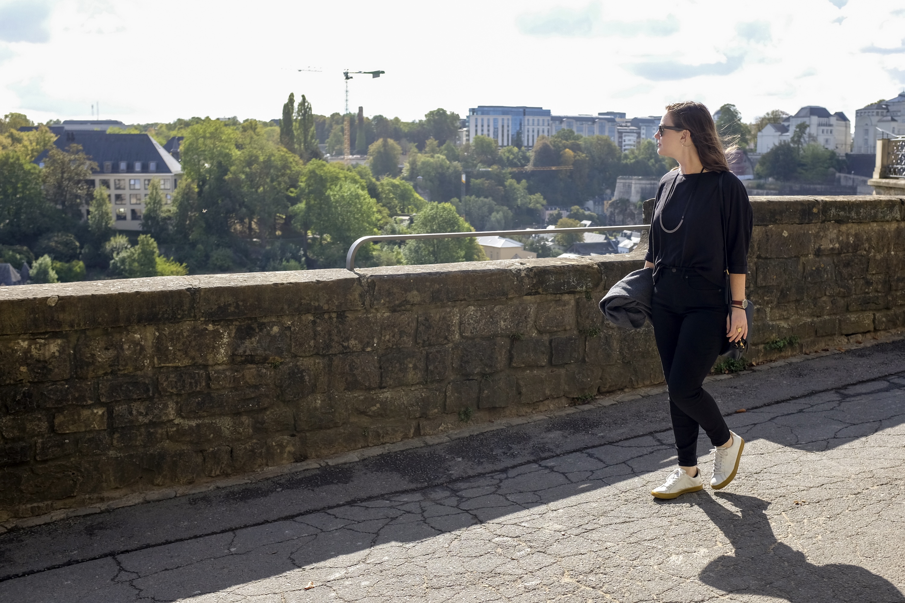 Alyssa wears a black top and jeans with sneakers in Luxembourg