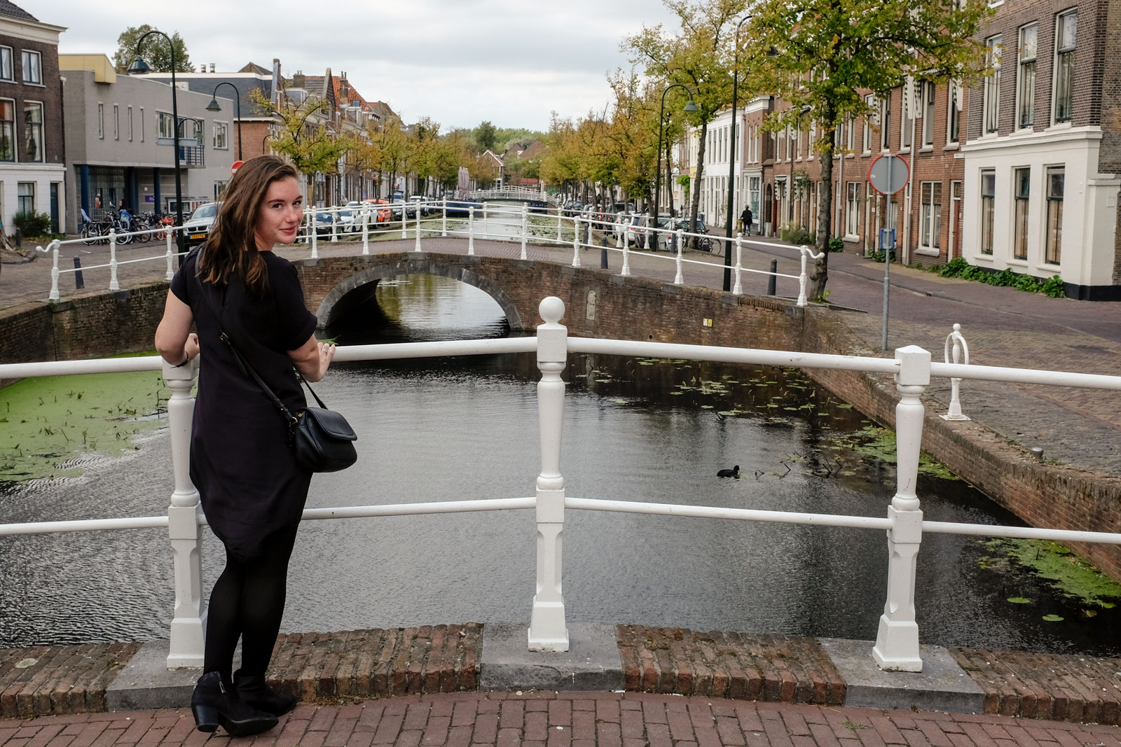 Alyssa wears a black silk dress with tights and boots in Delft