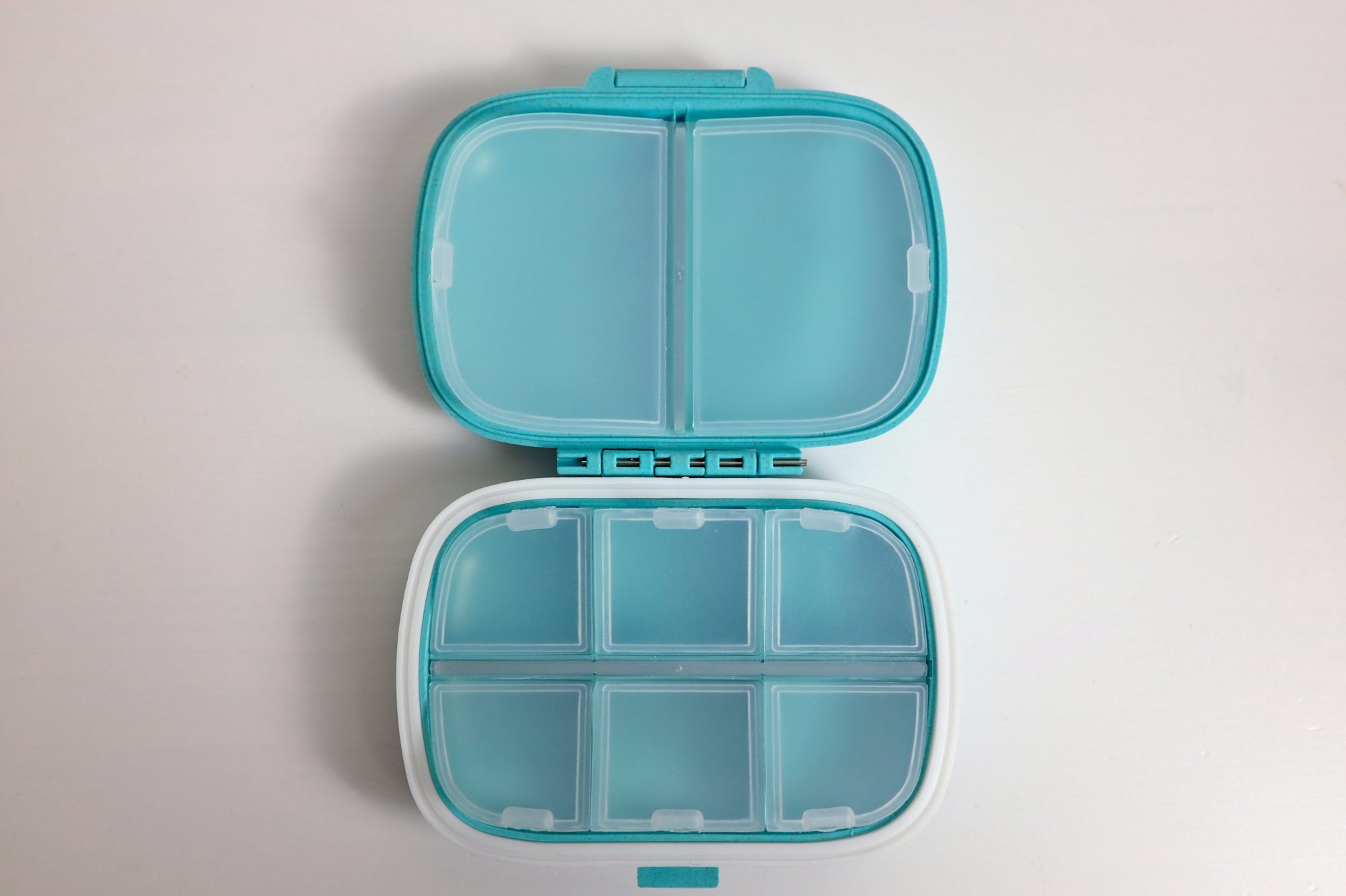 A blue plastic pillbox with eight interior containers