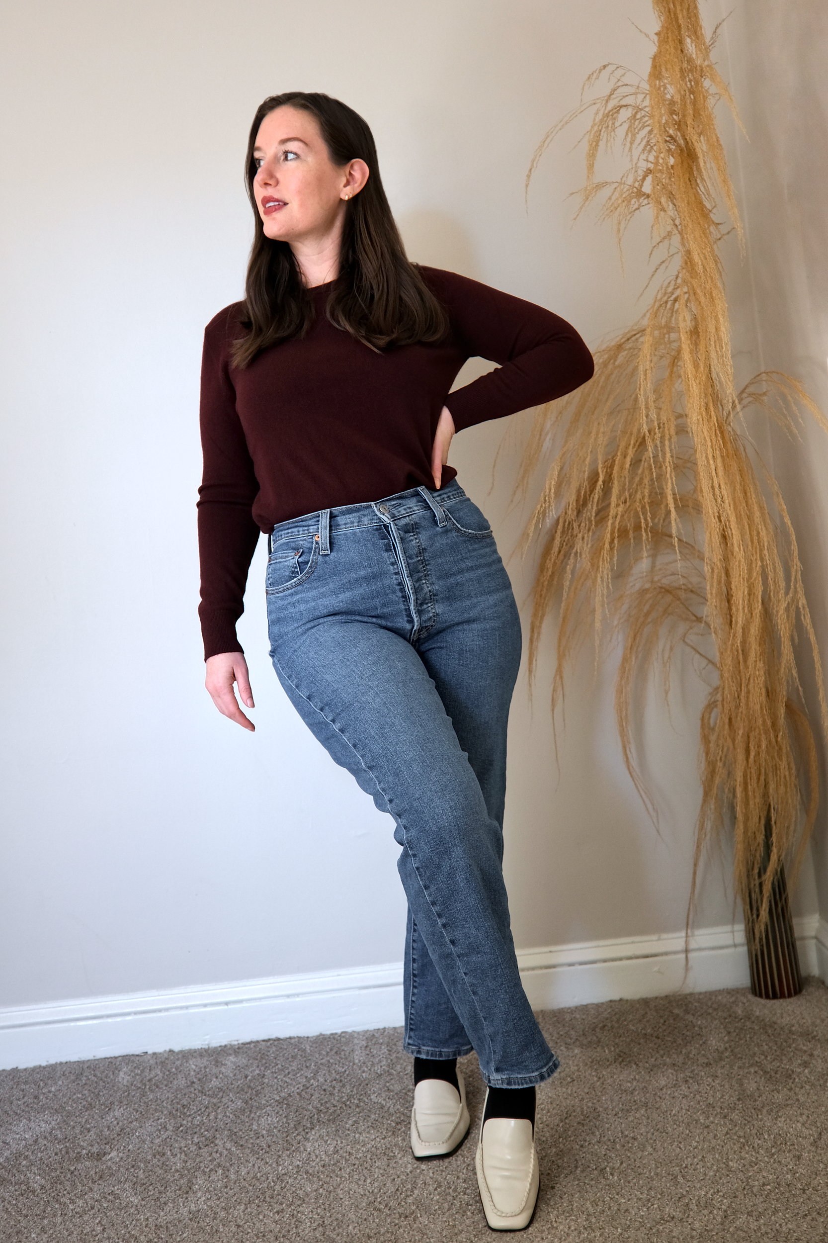 Alyssa wears a burgundy sweater from Quince with blue denim and white loafers 