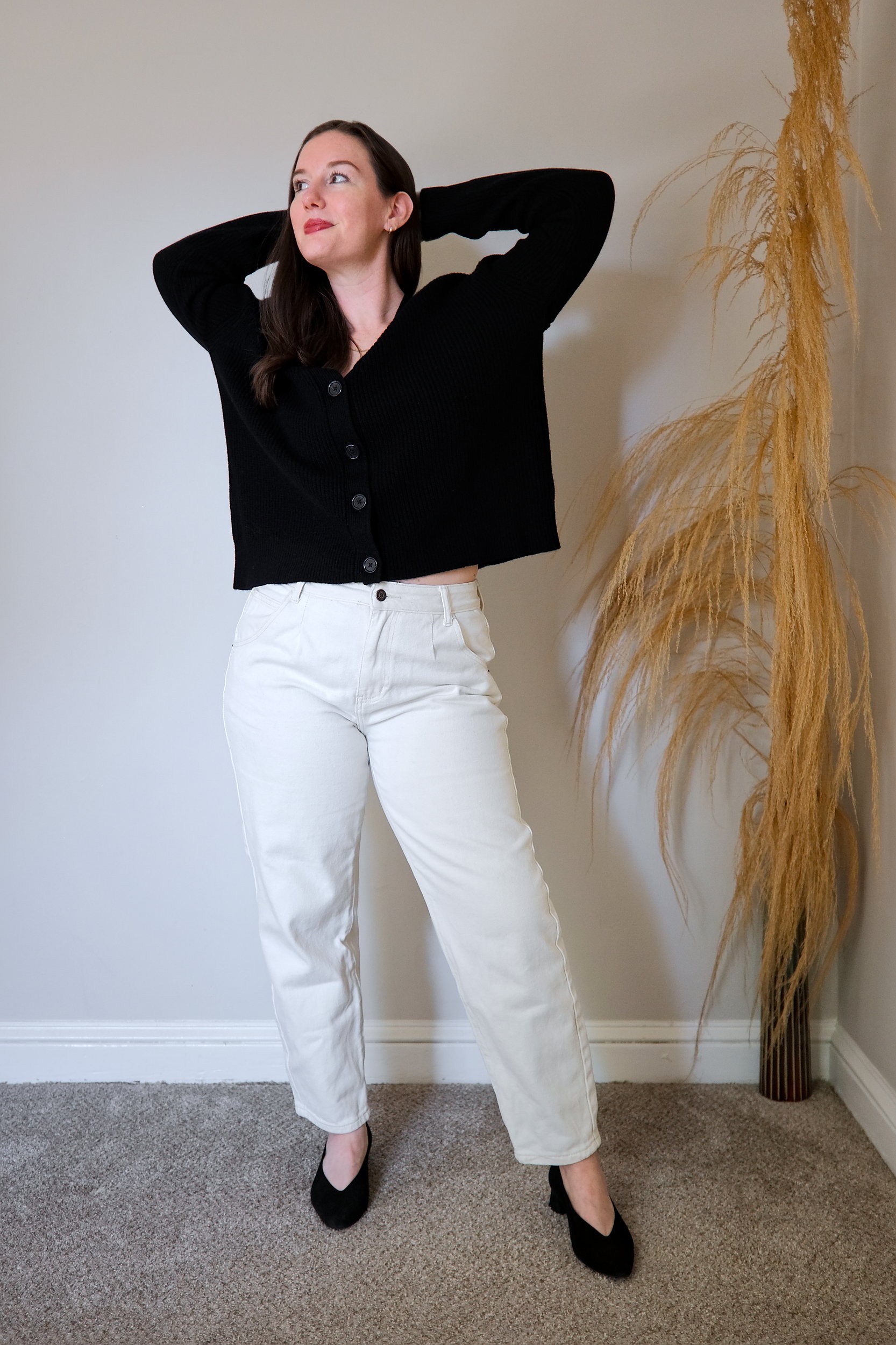 Alyssa wears the Mongolian Cashmere Fisherman Cropped Cardigan Sweater buttoned up with with white denim and heels, and raises her arms