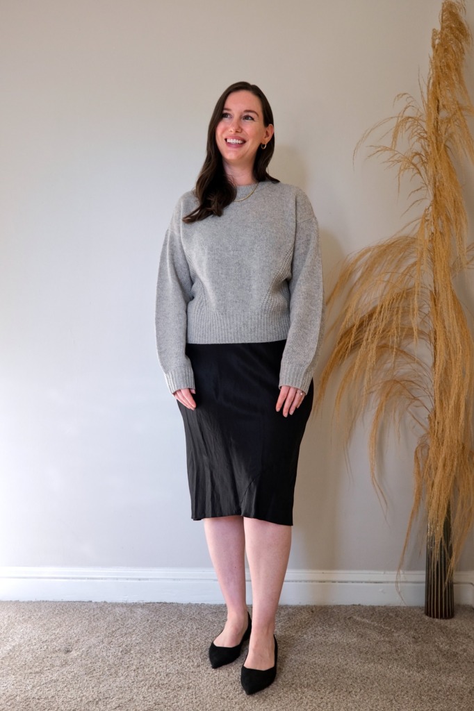 Alyssa wears the Quince yak sweater over a silk dress with black flats. She is smiling and looking away from the camera