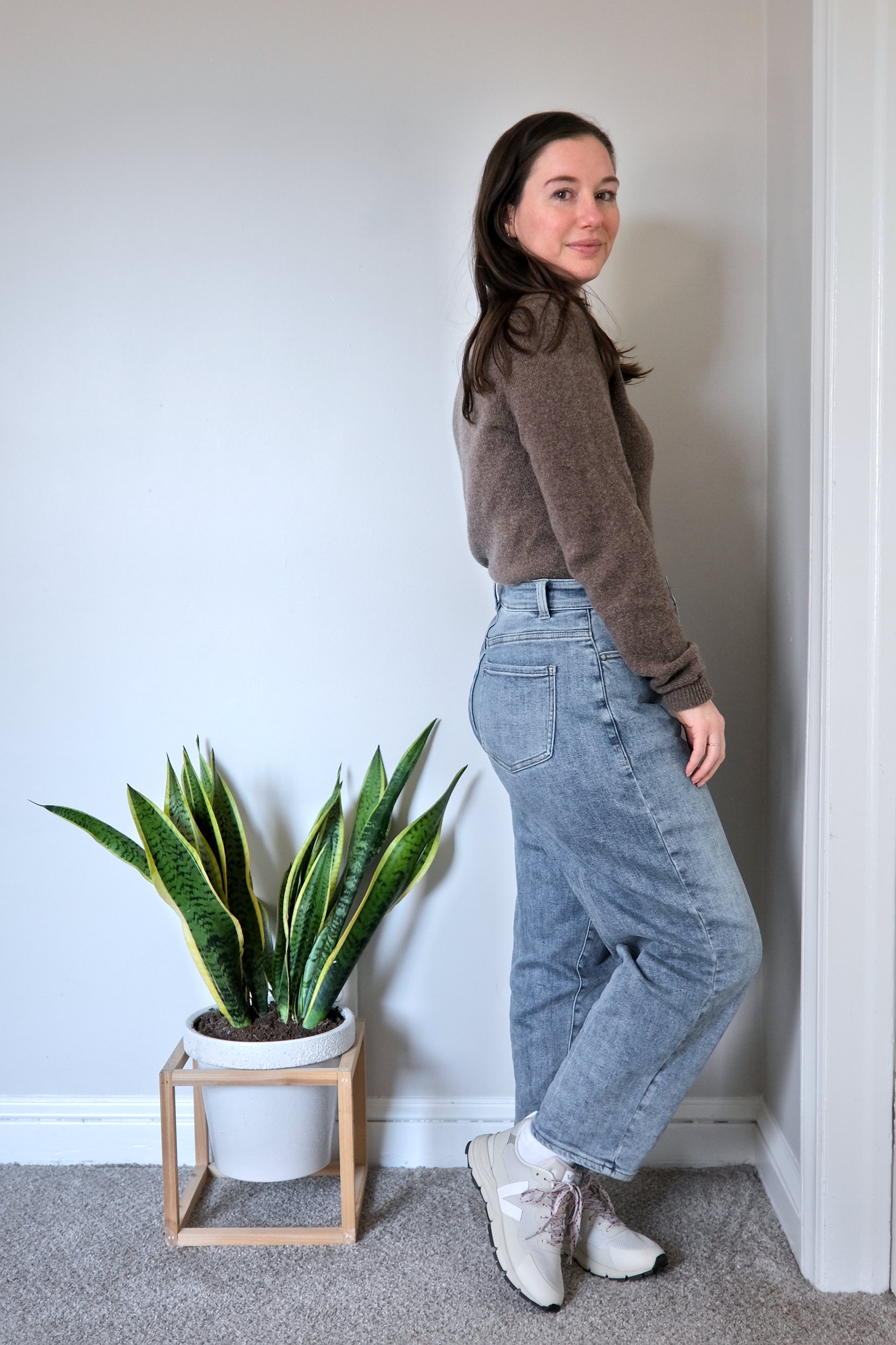 Alyssa wears a yak sweater from Quince in soft brown with sneakers, and turns in profile to the camera