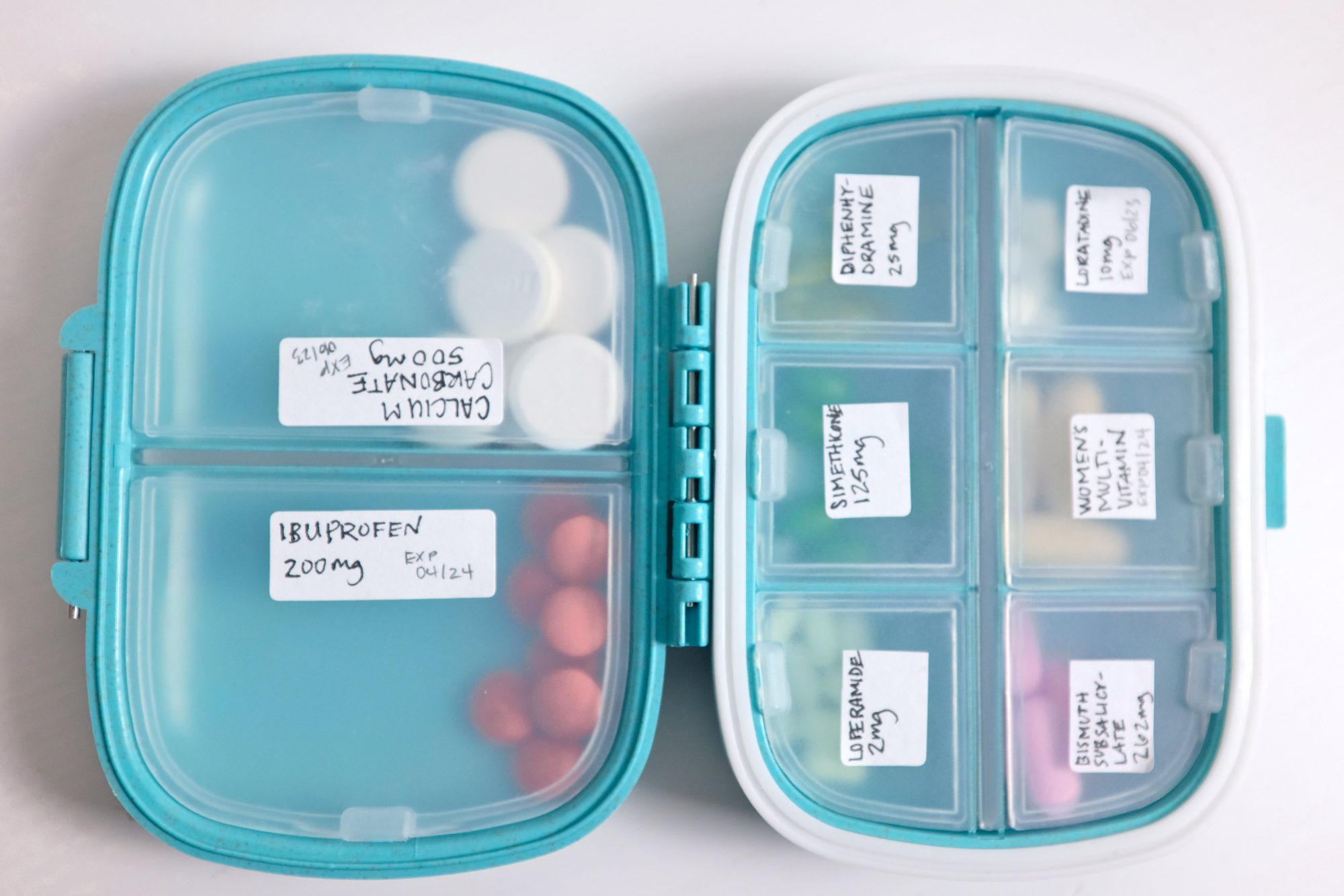 An open pillbox containing pills, each with a label