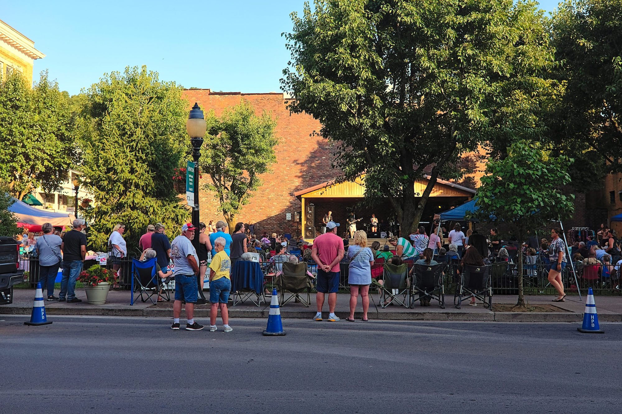 A crowd gathers to listen to music in a park