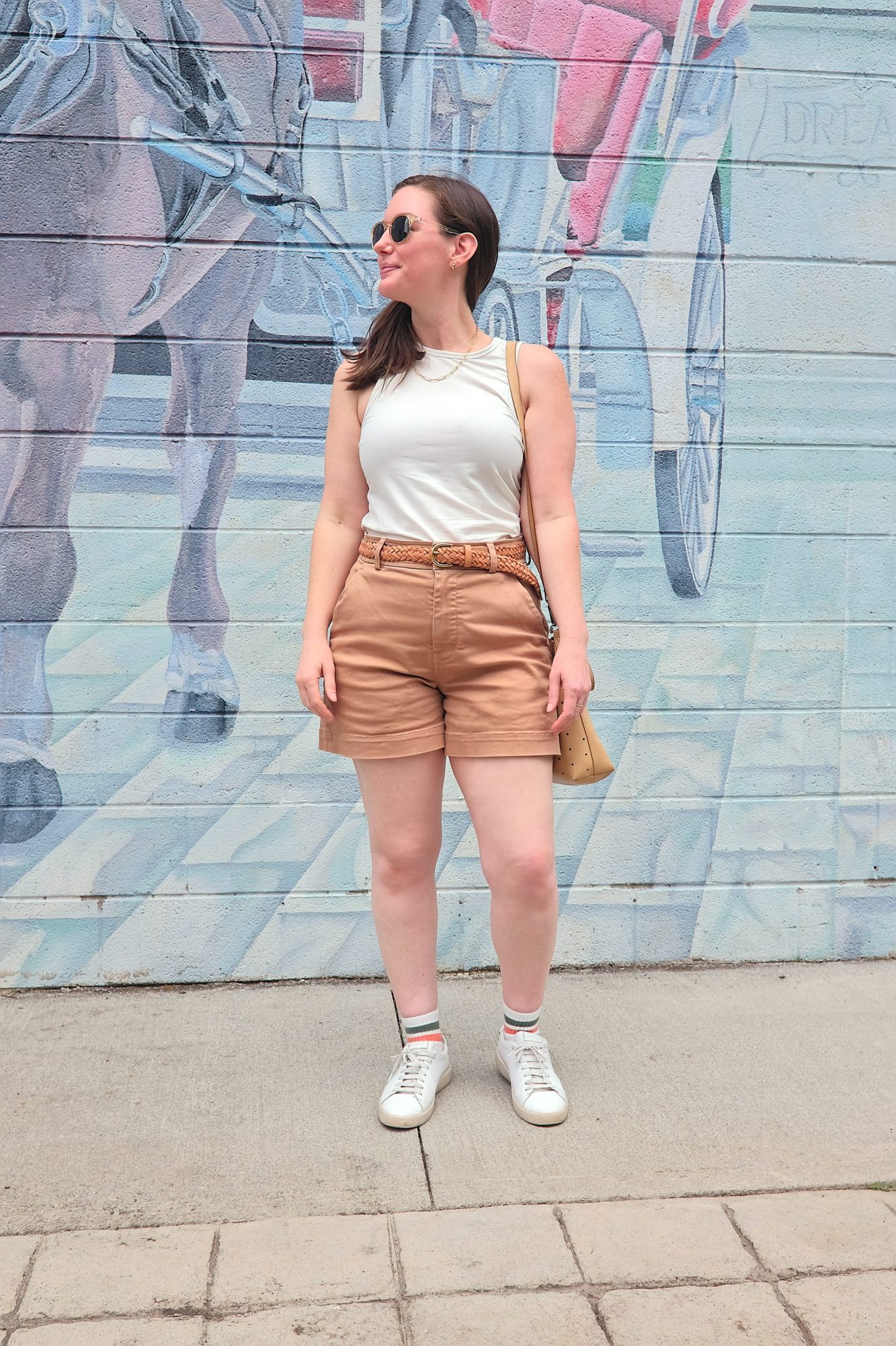 Alyssa wears a white tank, tan shorts, and sneakers