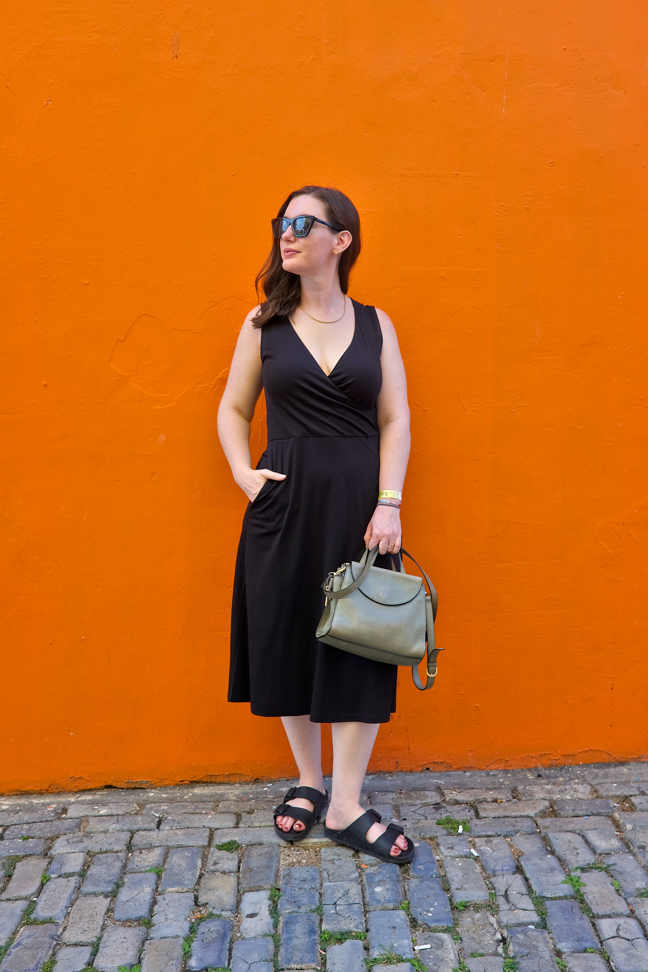 Alyssa in a black dress in front of an orange wall in Old San Juan