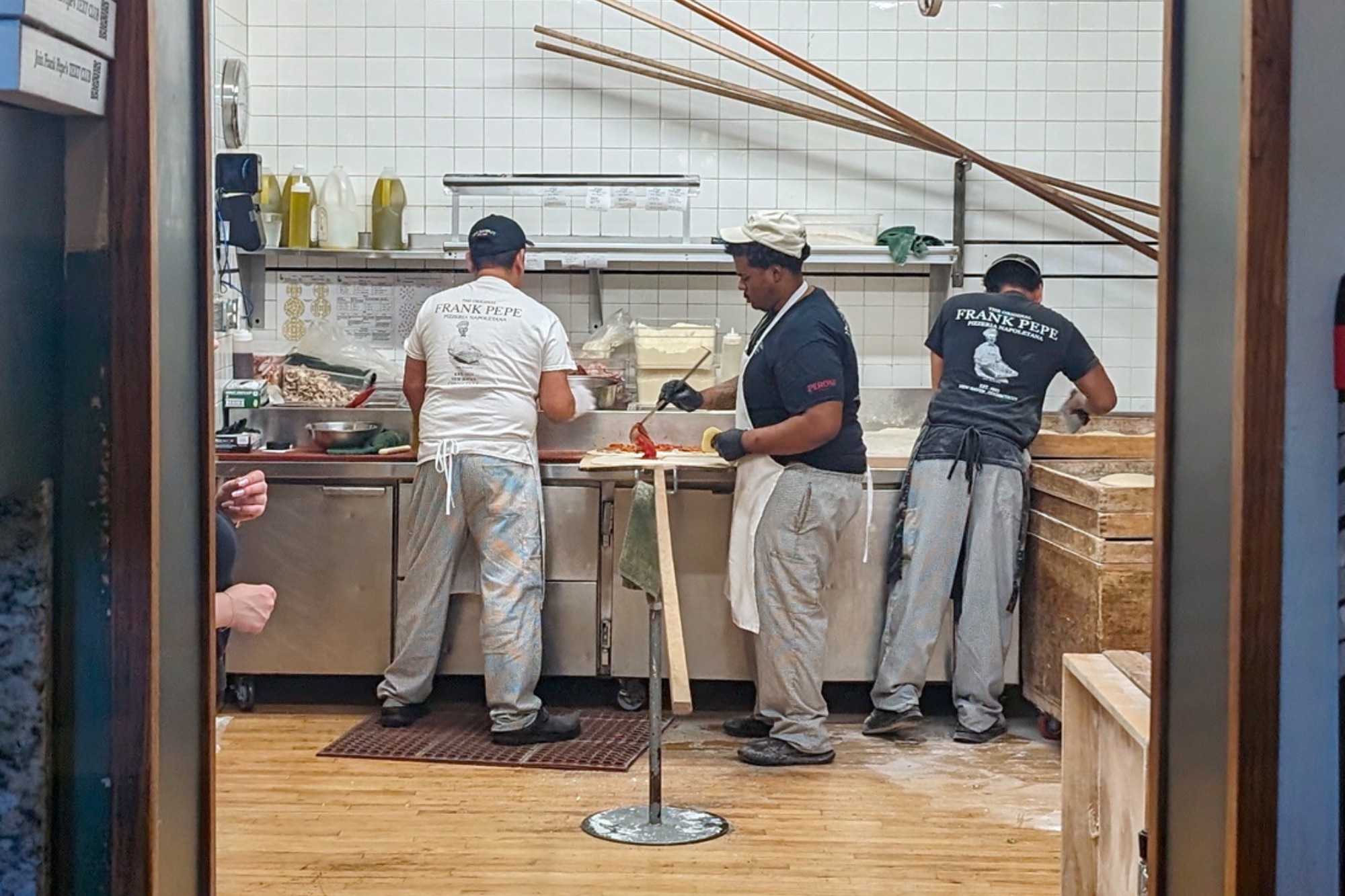 Three workers make pizza at Frank Pepe's