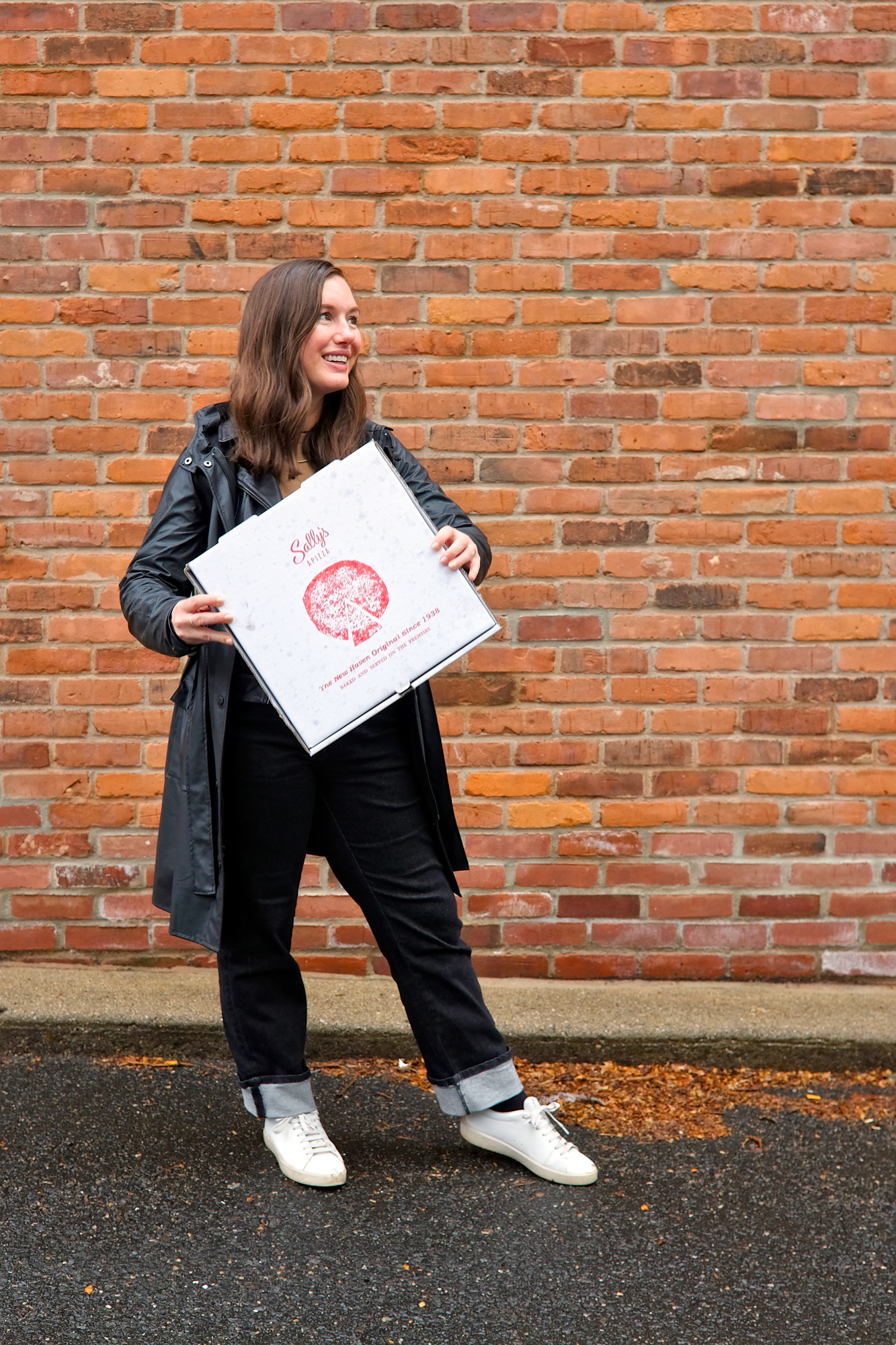 Alyssa holds a box of pizza from Sally's