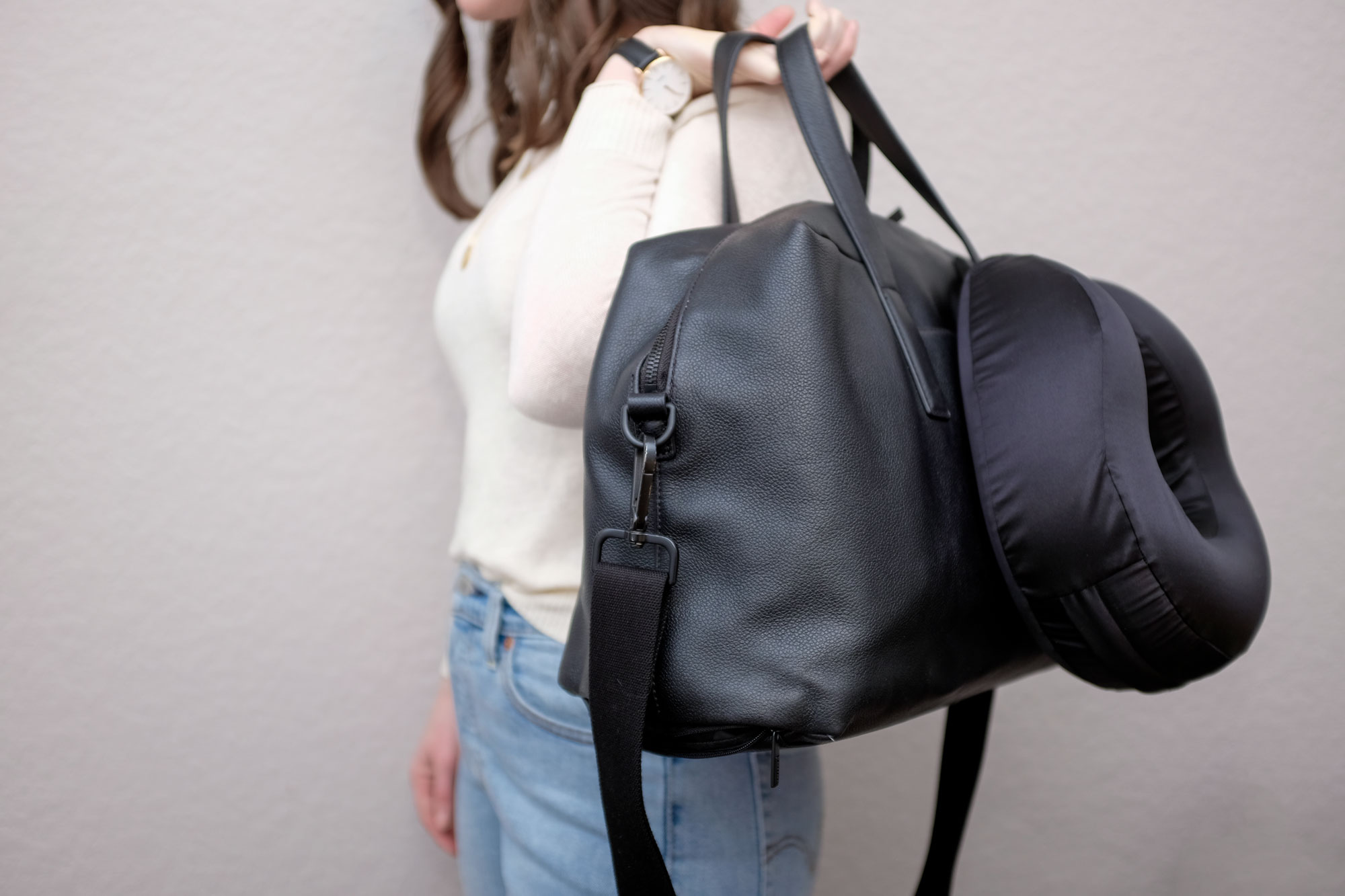 Alyssa holds a duffel bag with a pillow clipped to it