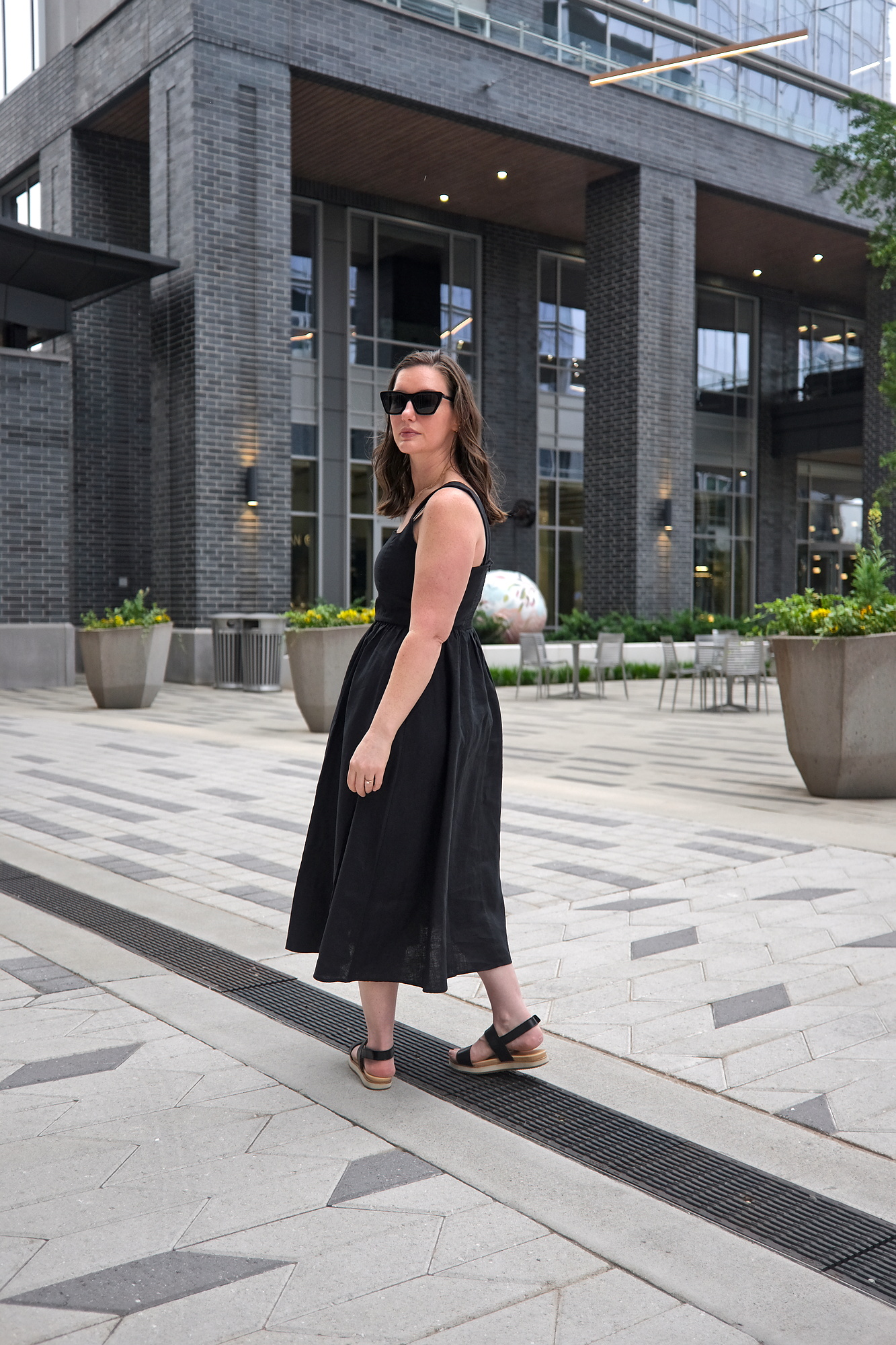 Alyssa wears a fit and flare linen dress and looks back at the camera