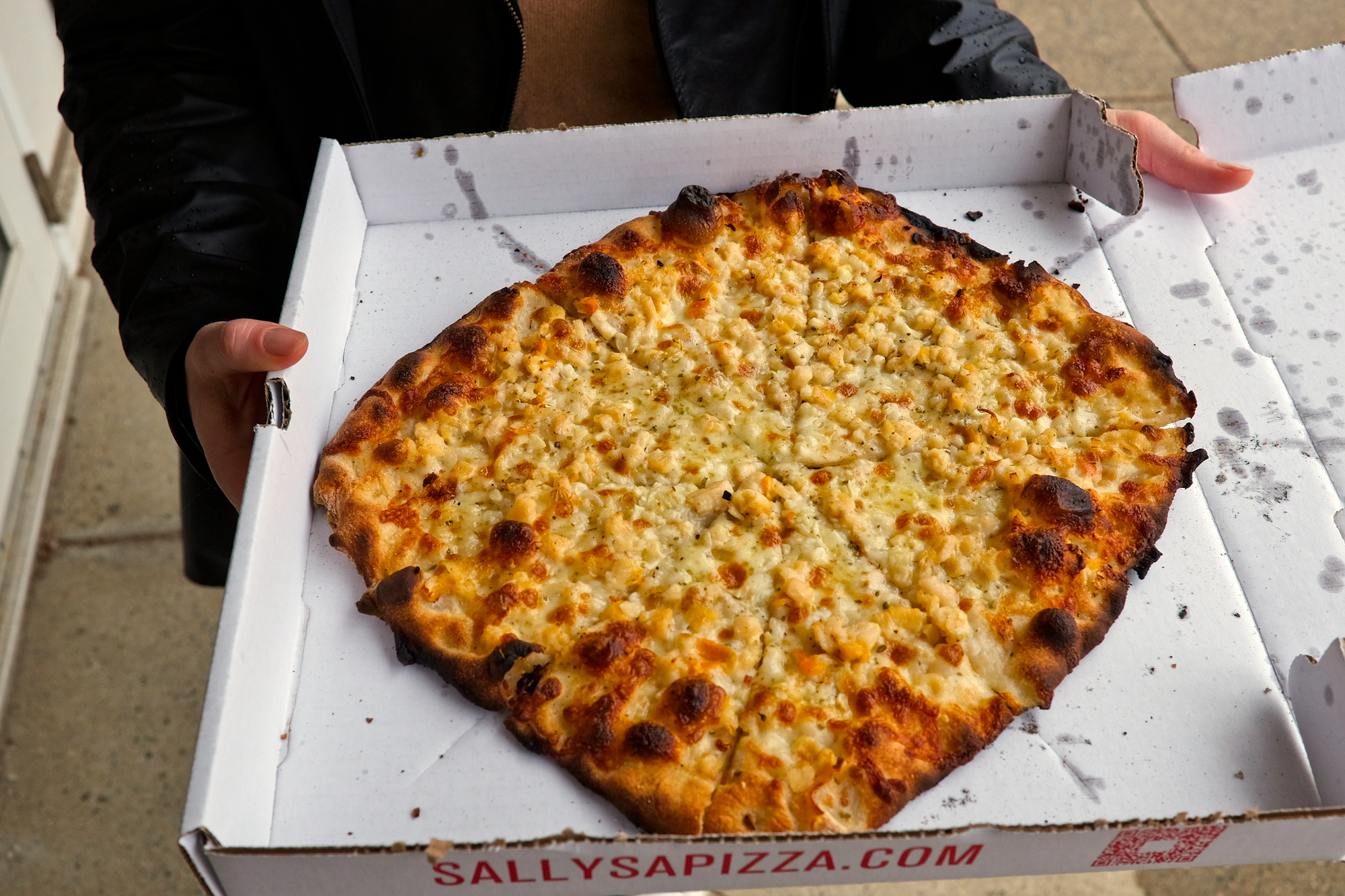 Alyssa holds a box of clam pizza from Sally's