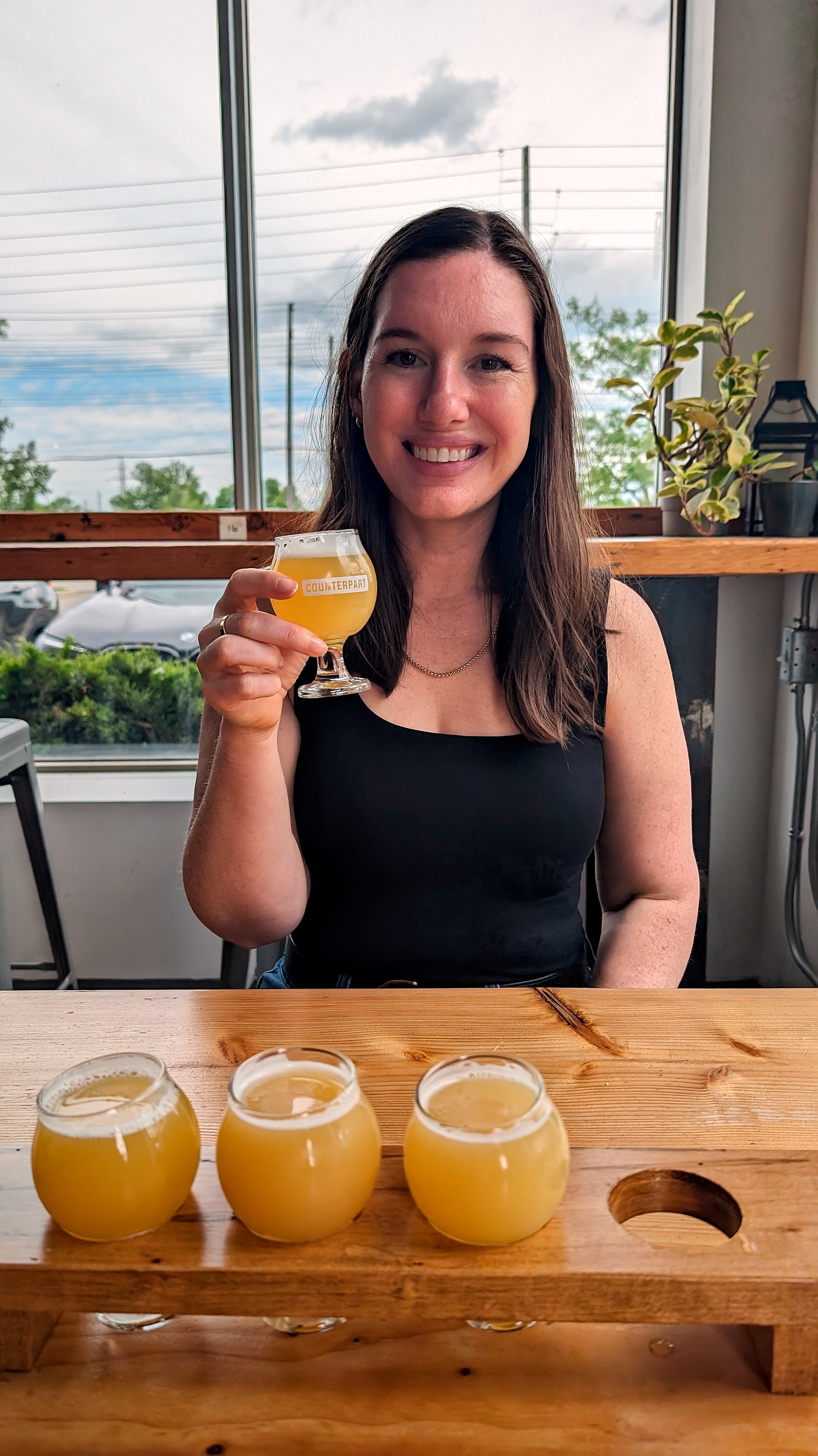 Alyssa holds a beer from a flight at Counterpart Brewing