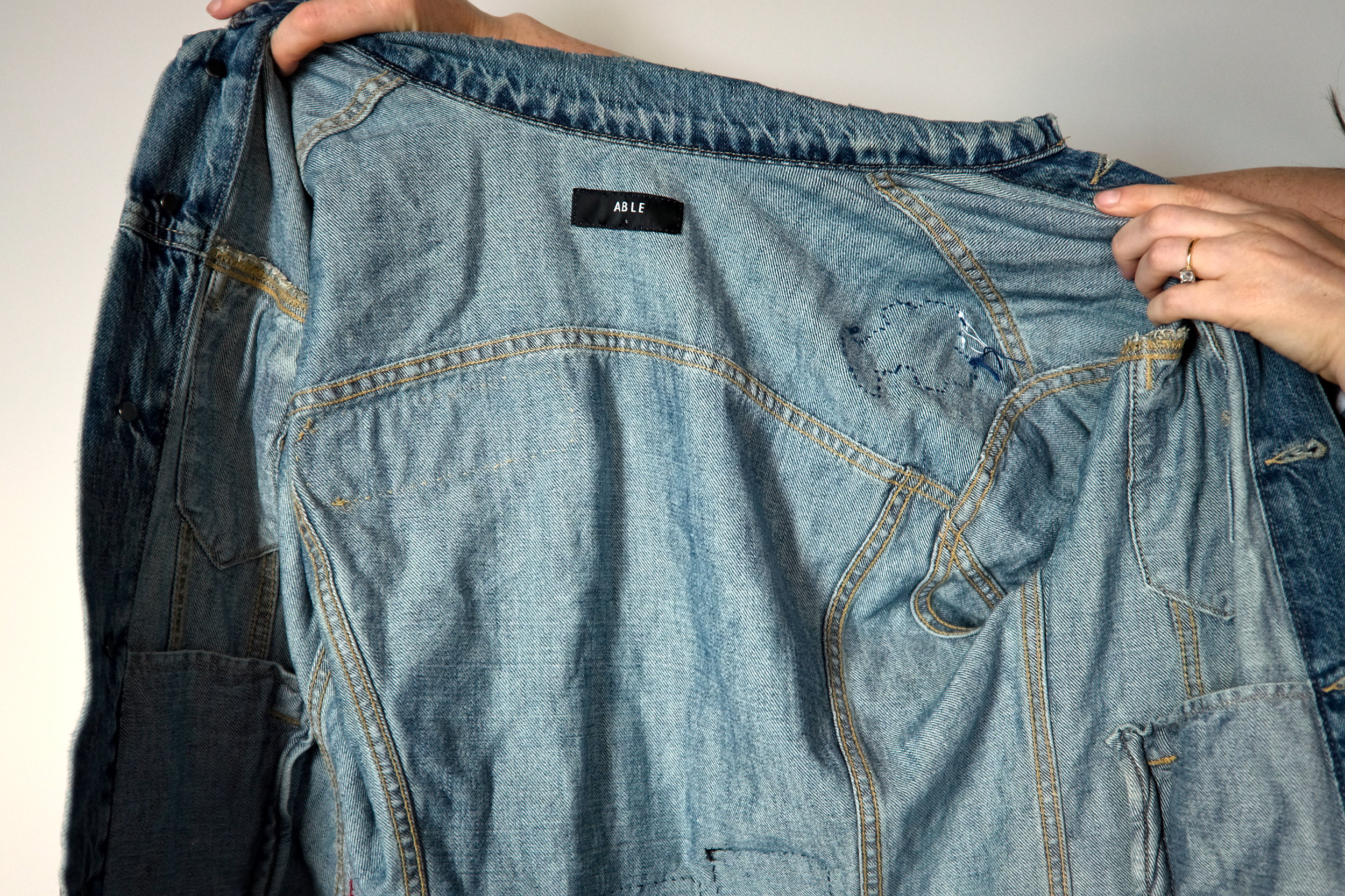 Alyssa holds a jean jacket and shows the label