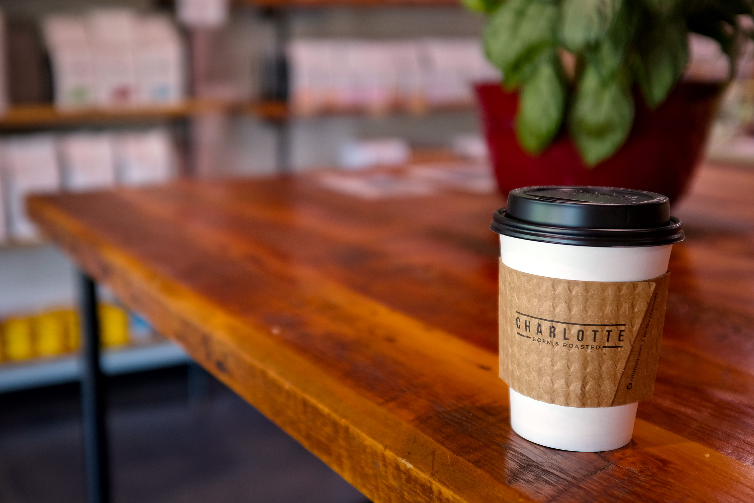 A coffee cup that reads "Charlotte Born and Roasted" on the sleeve