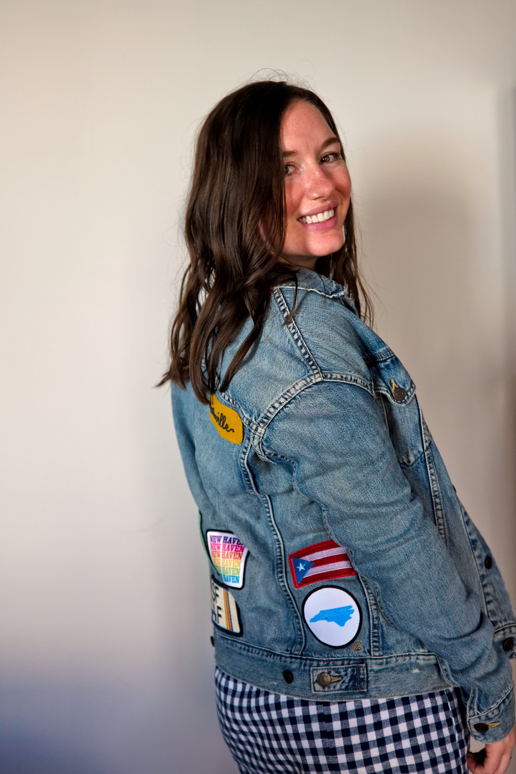 Alyssa wears a denim patch jacket with a gingham dress