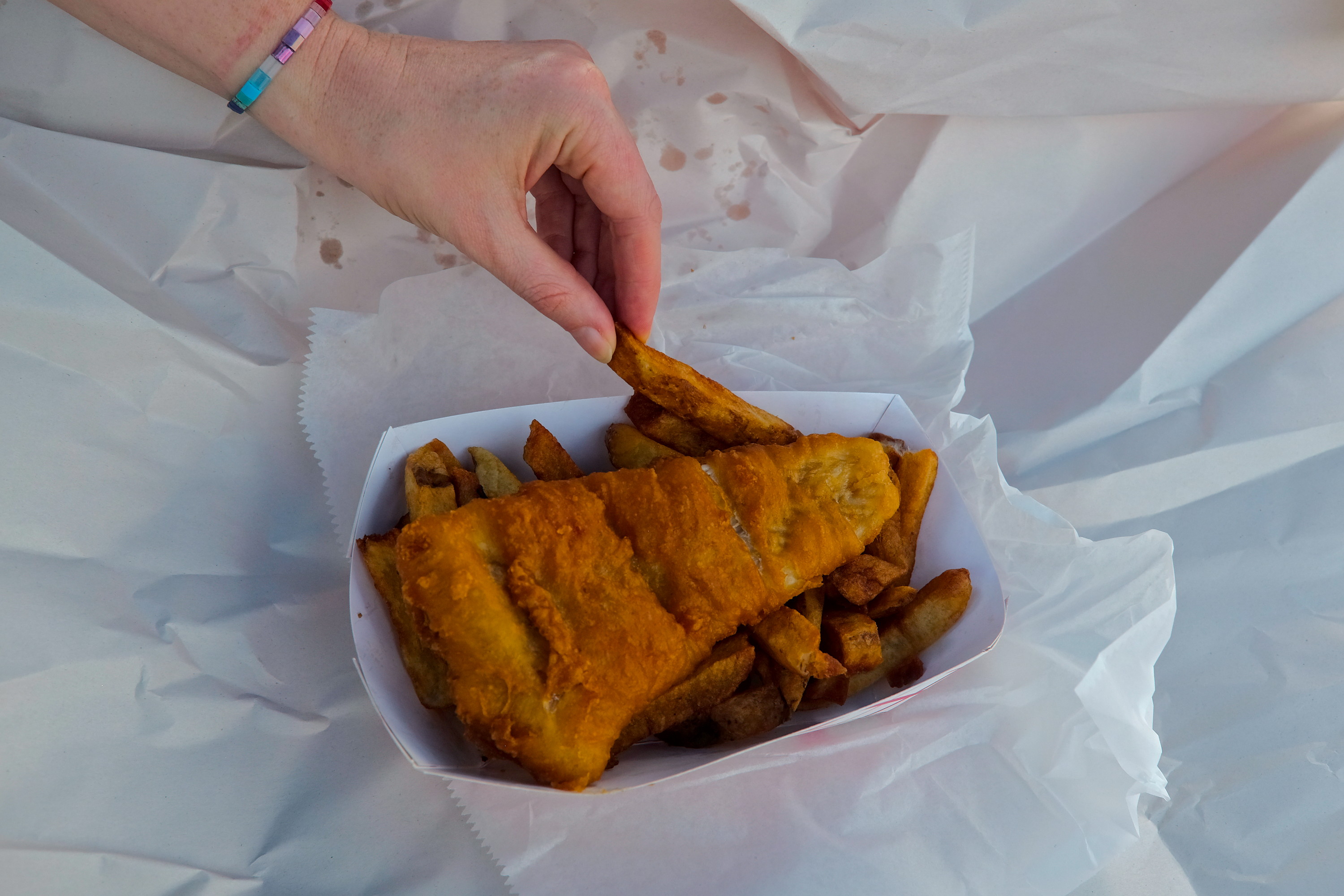 Alyssa pulls a fry from a container of fish and chips