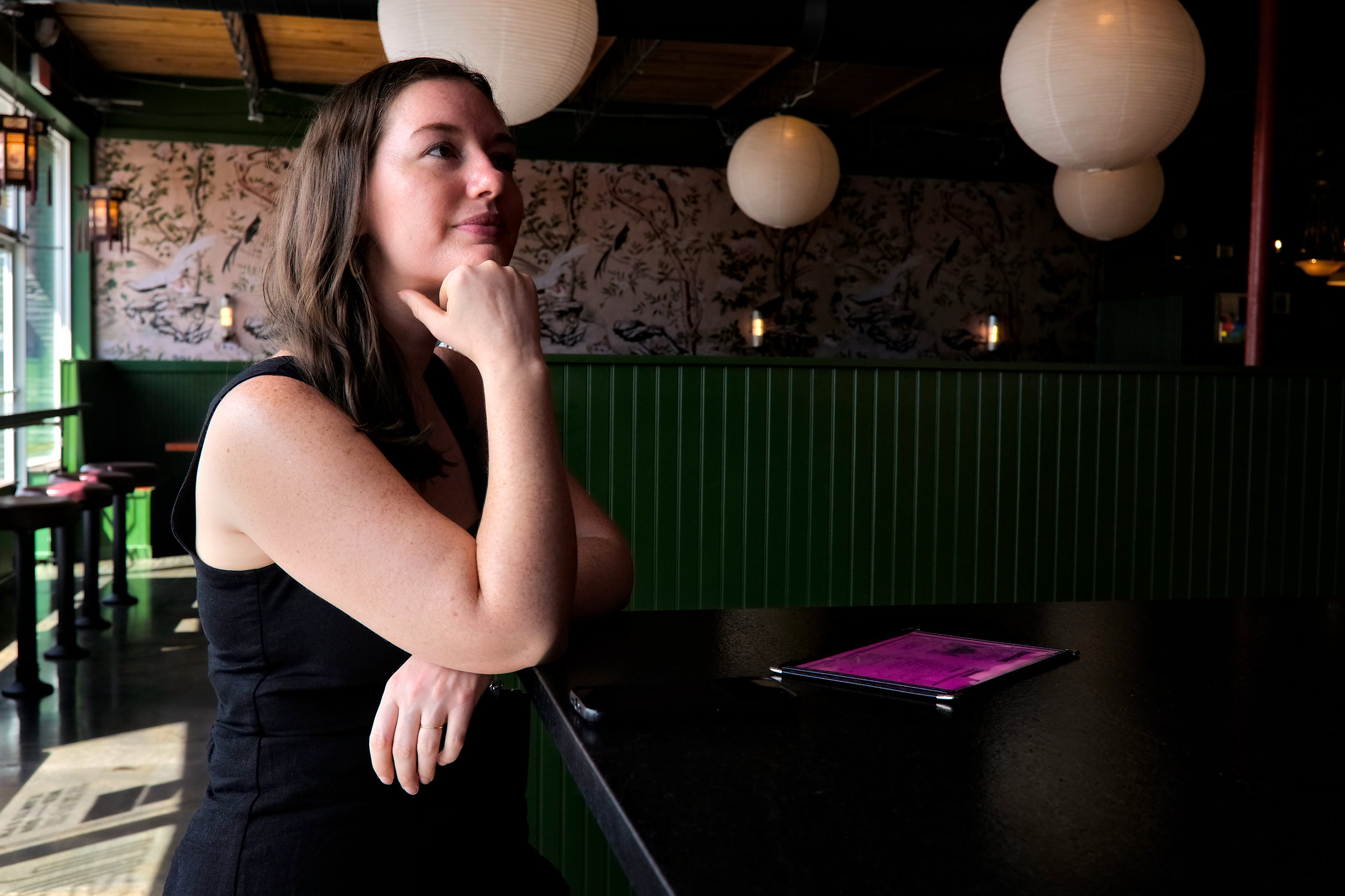 Alyssa rests her head in her hand at a restaurant bar in Charleston