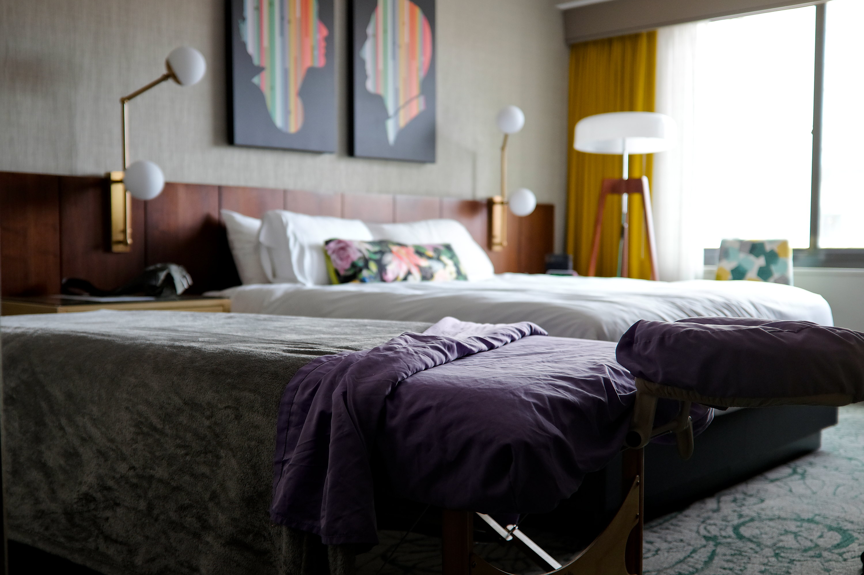 A hotel room with a massage table set up next to the bed