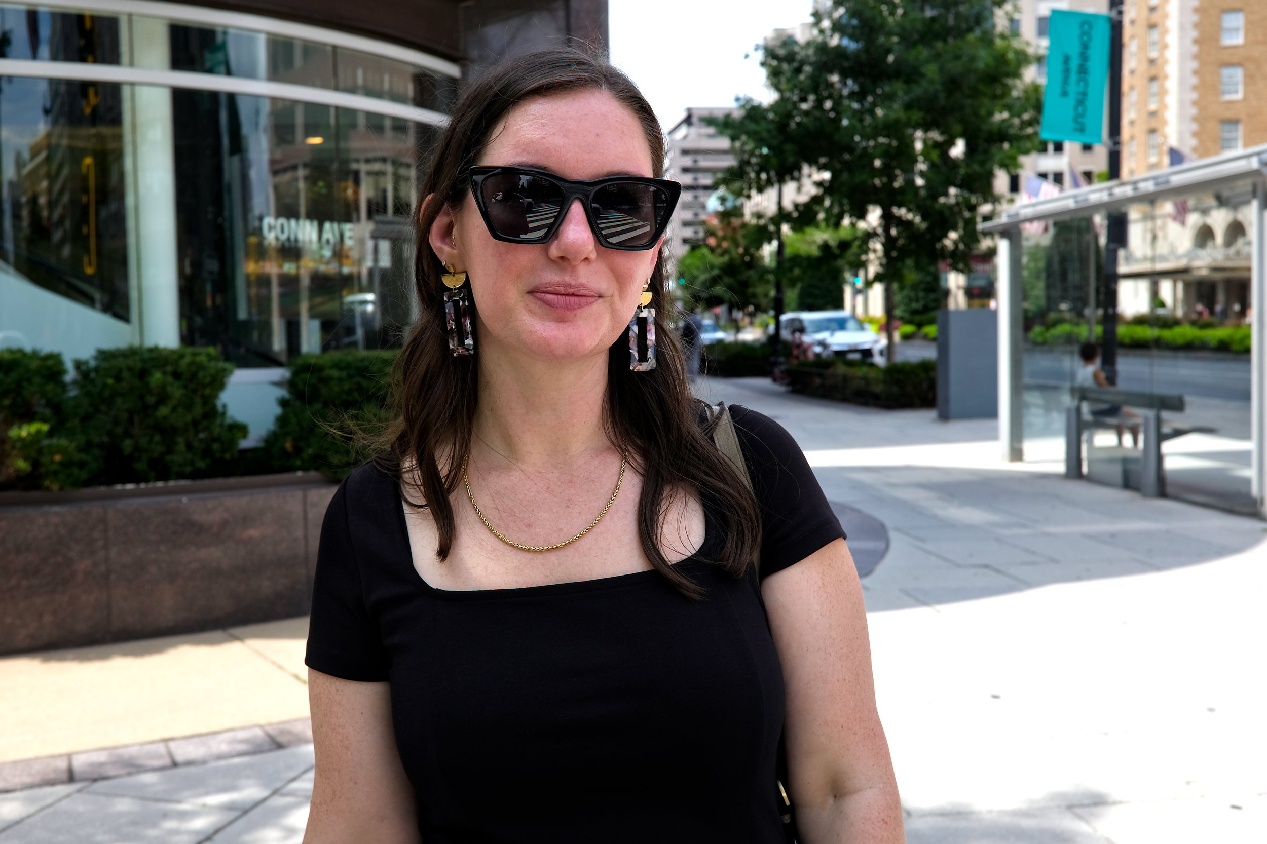 Alyssa wears a black dress with statement earrings and sunglasses