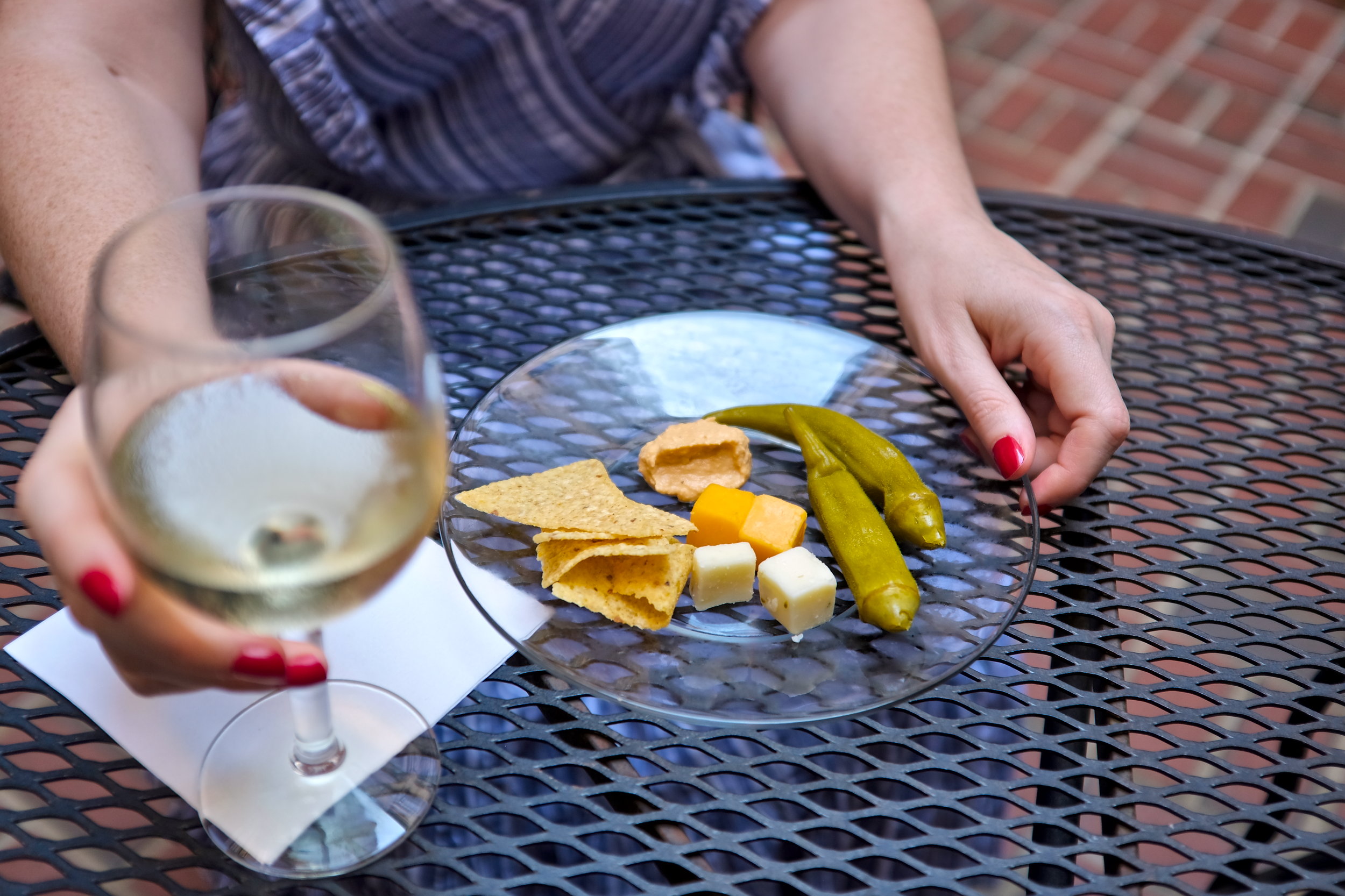 Alyssa holds a glass of wine and a cheese plate