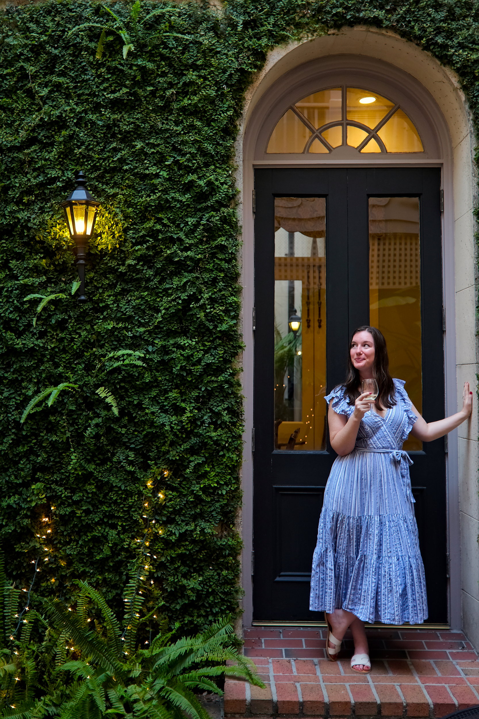 Alyssa holds a glass of wine in a doorway at Kings Courtyard Inn