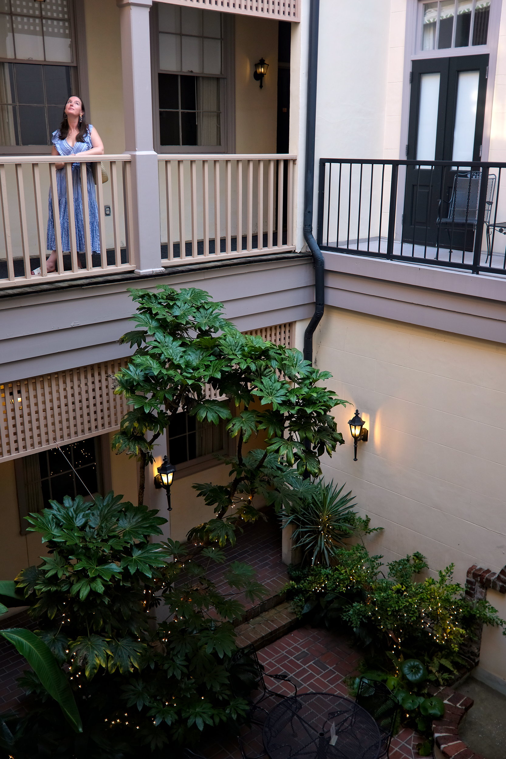 Alyssa looks up at the sky from a courtyard. She is wearing a striped dress.