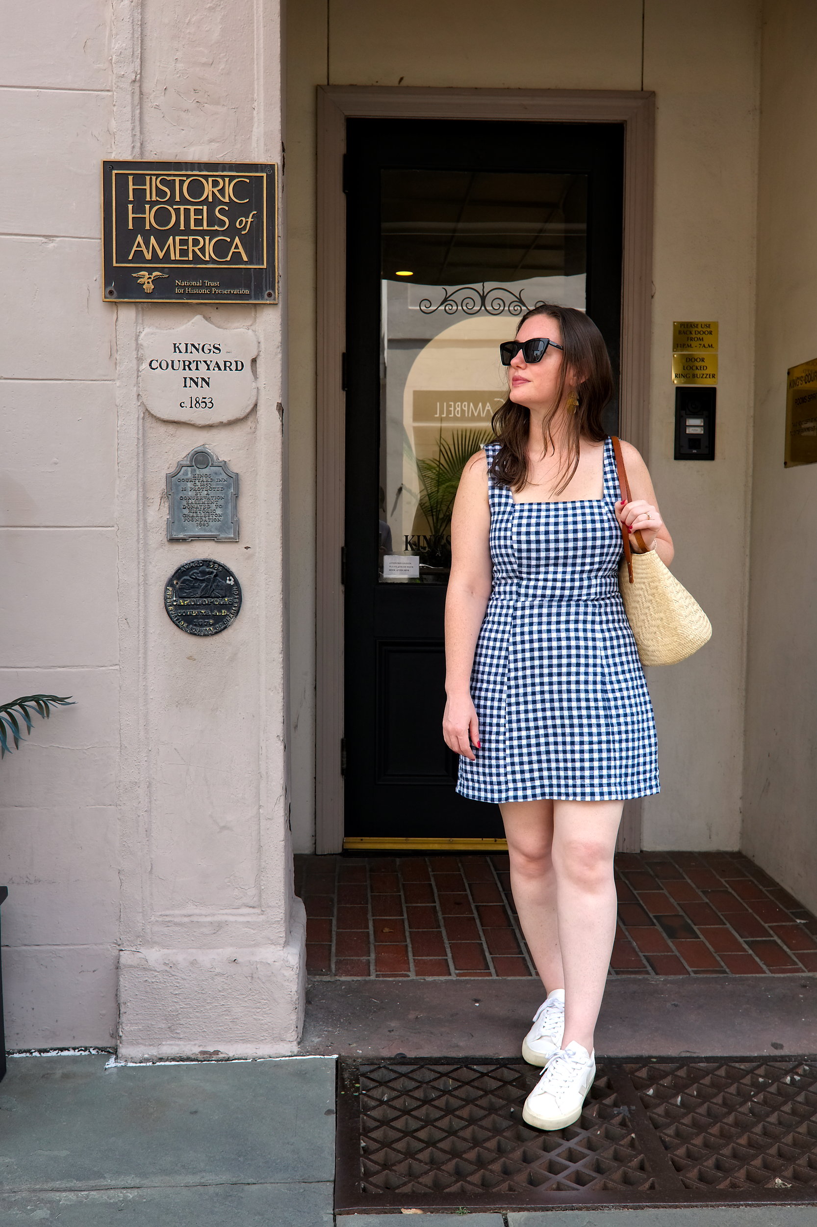 Alyssa wears a blue gingham dress with white sneakers and a basket purse from her Charleston packing list