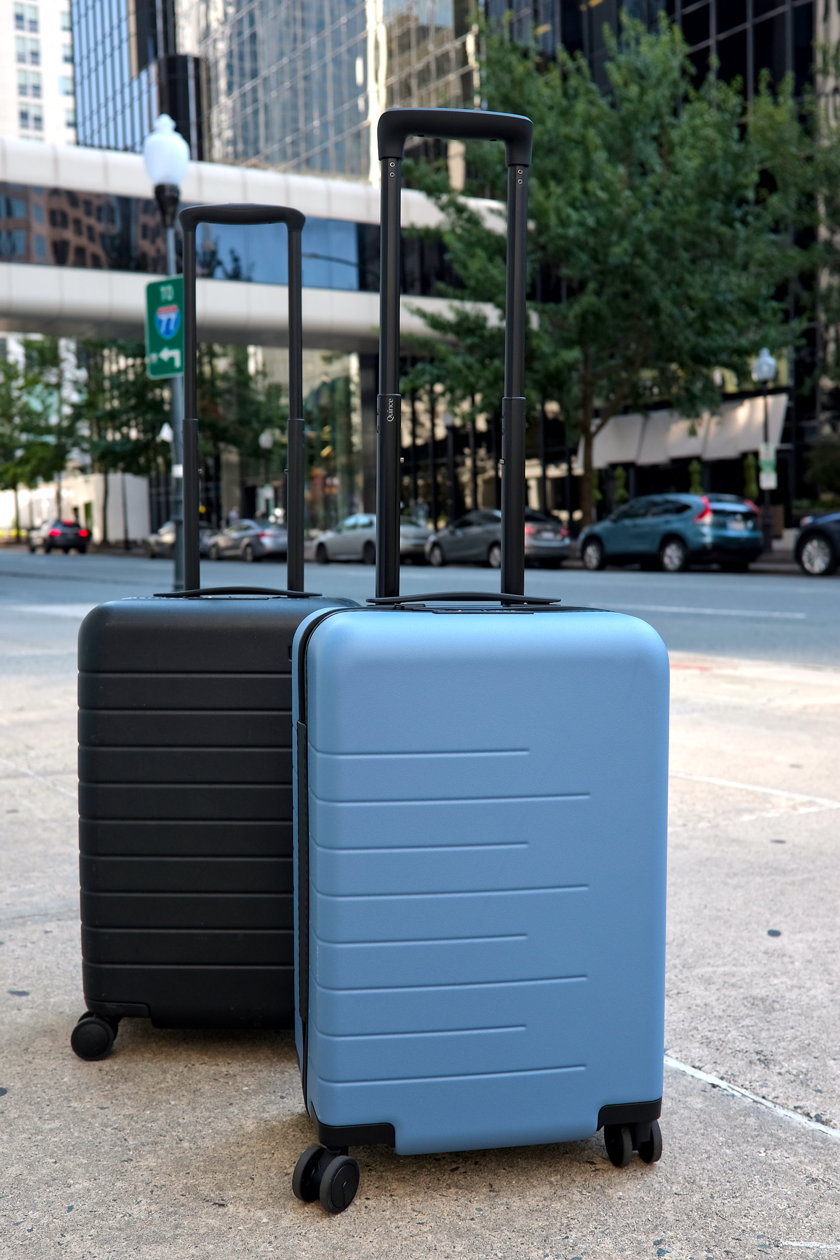 The Away and Quince Carry-On suitcases are on a Charlotte sidewalk