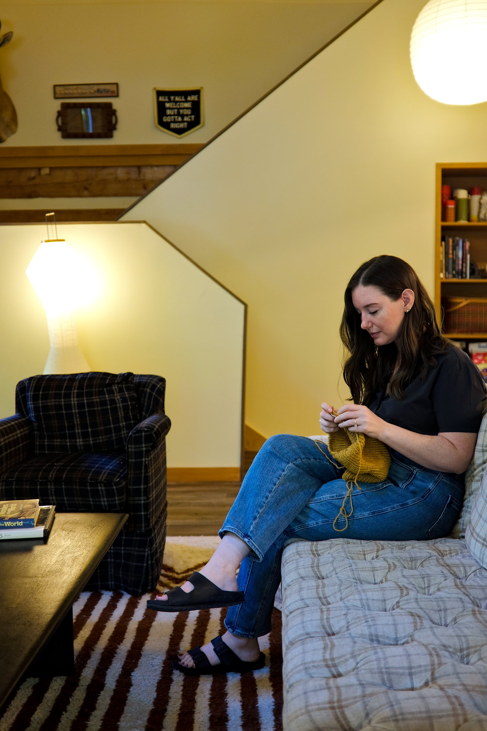 Alyssa knits on a cabin sofa