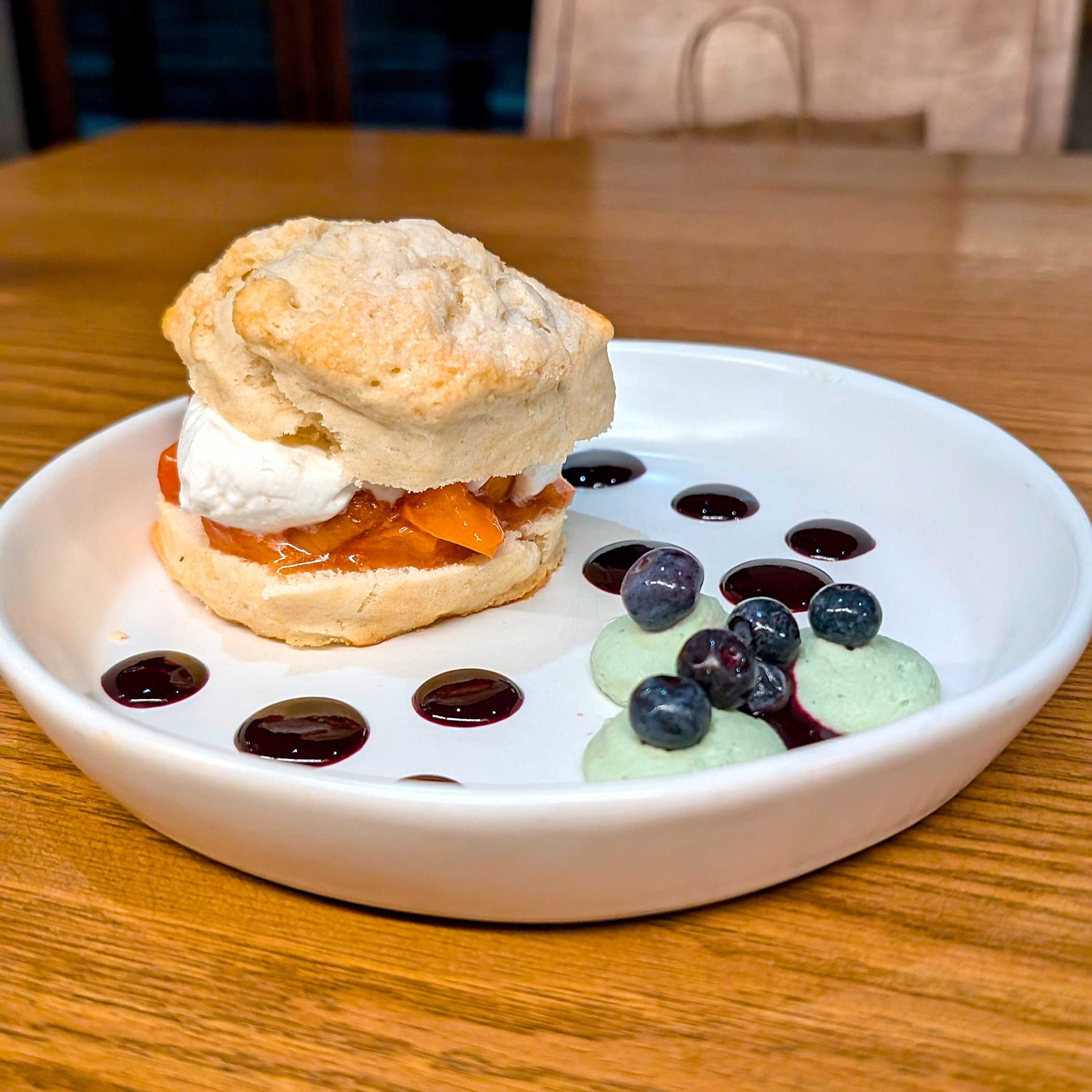 A peach shortcake with blueberry and mint whipped cream