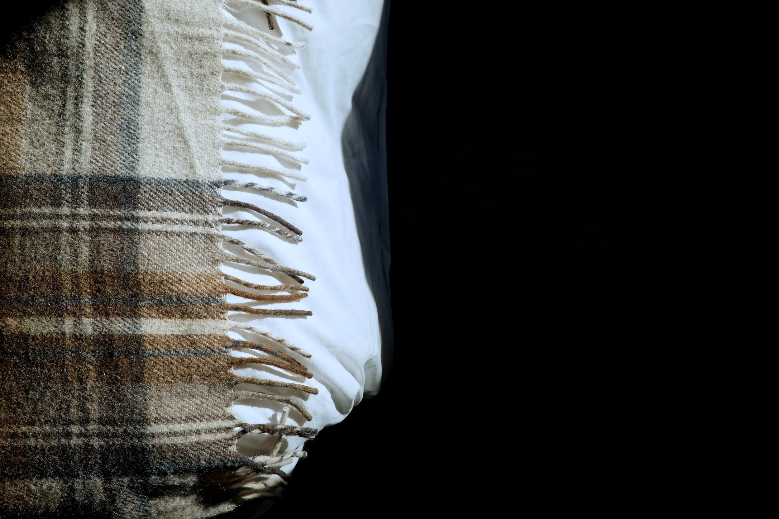 A woolen blanket at the foot of the bed