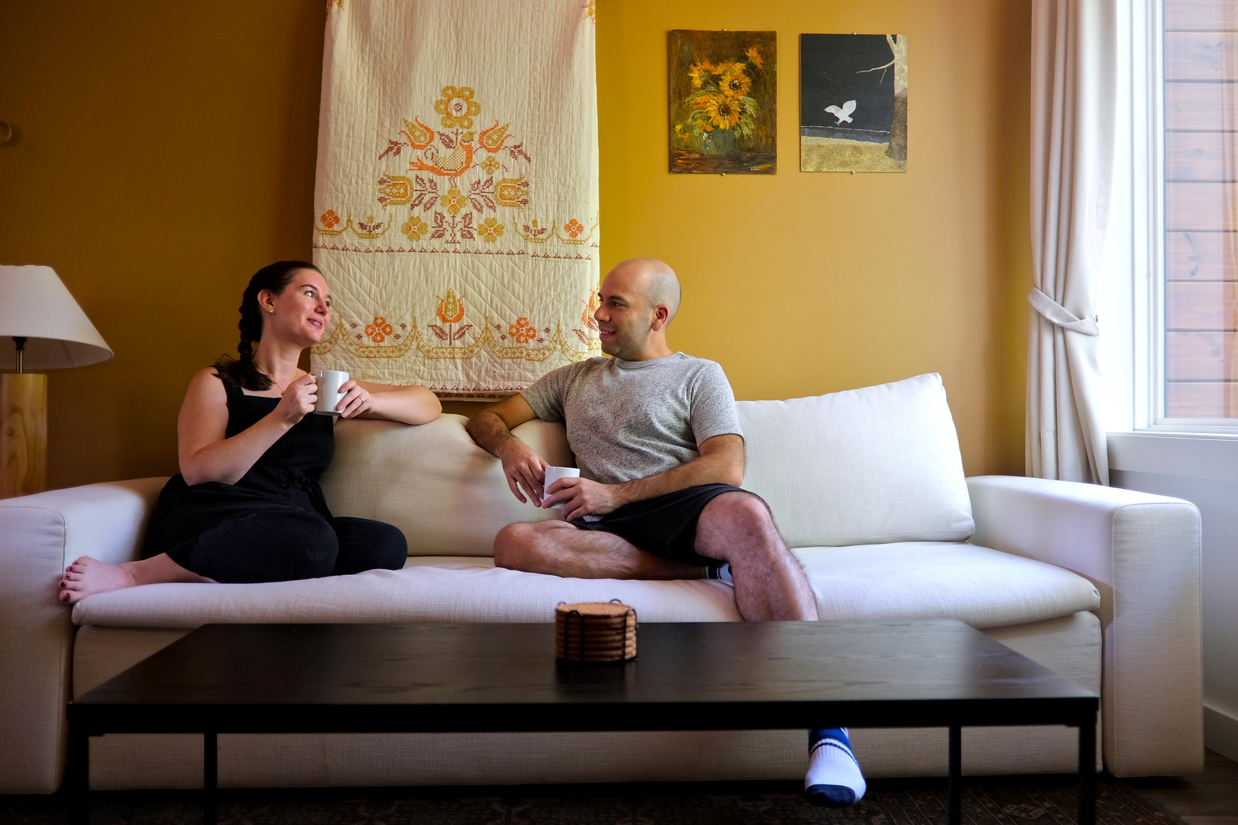 Alyssa and Michael sit on a sofa in a Roamstead cabin