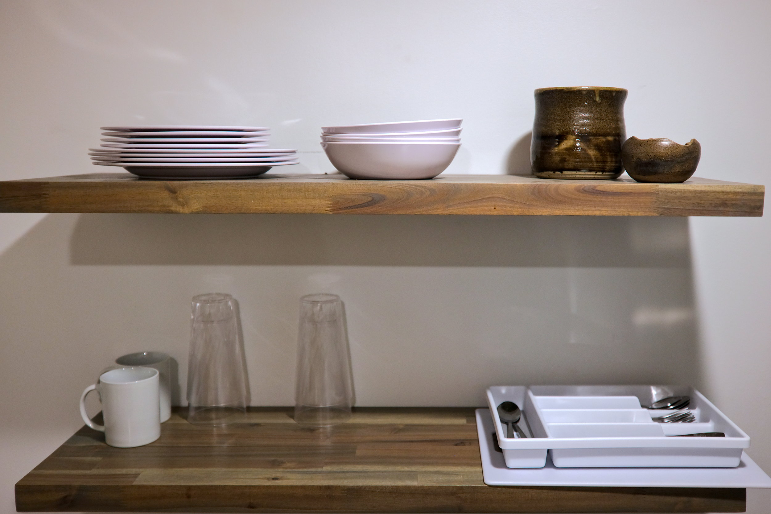 Plates, cups, and utensils on a shelf in the cabin