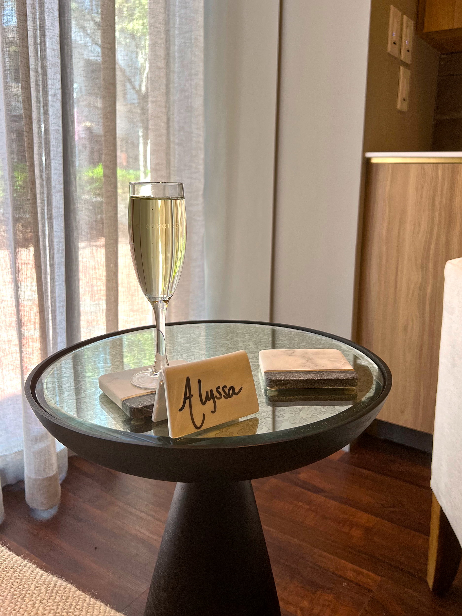 A glass of champagne with a card that reads Alyssa