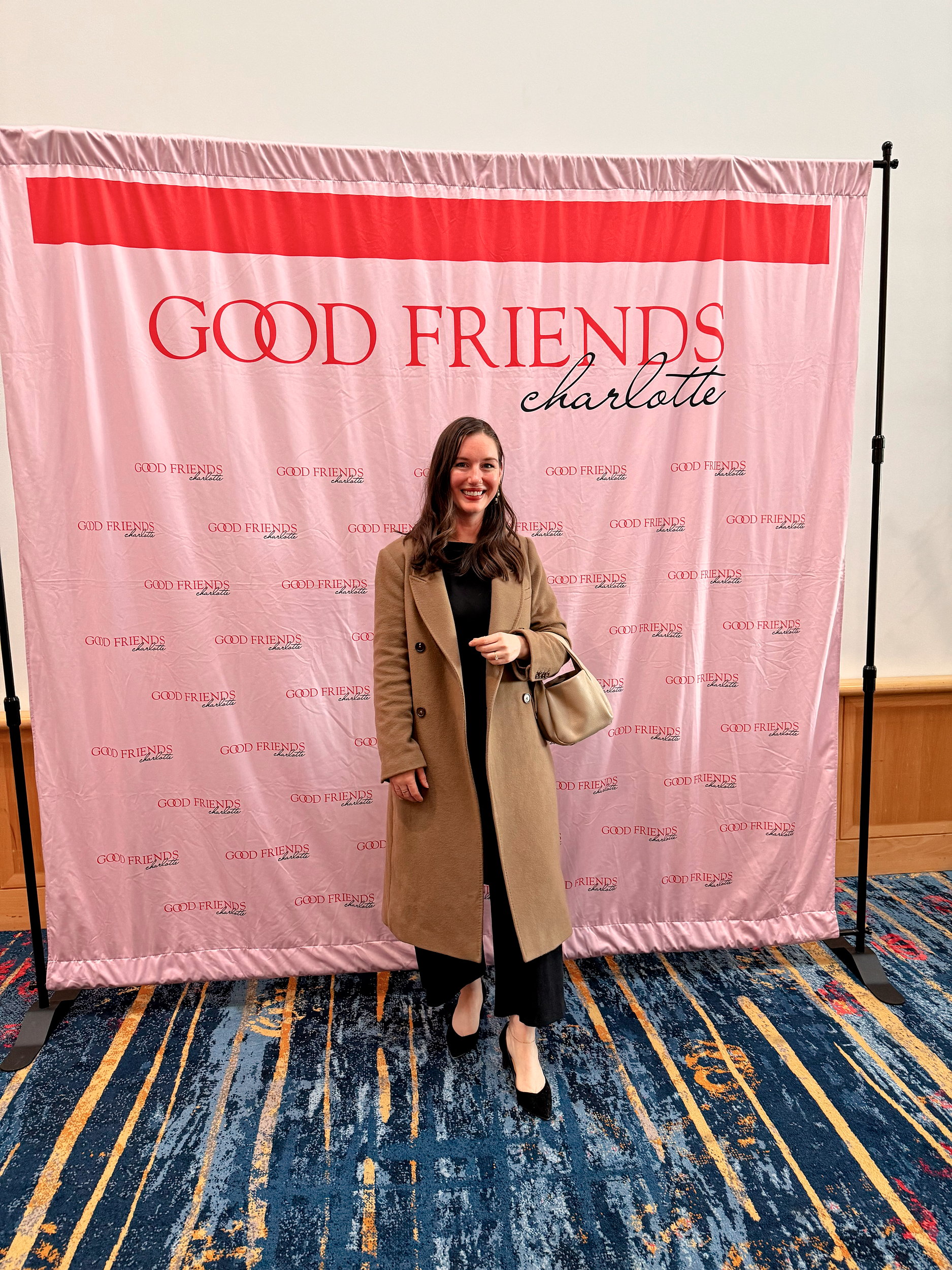 Alyssa at the Gather & Give Fundraiser in front of a Good Friends Charlotte banner