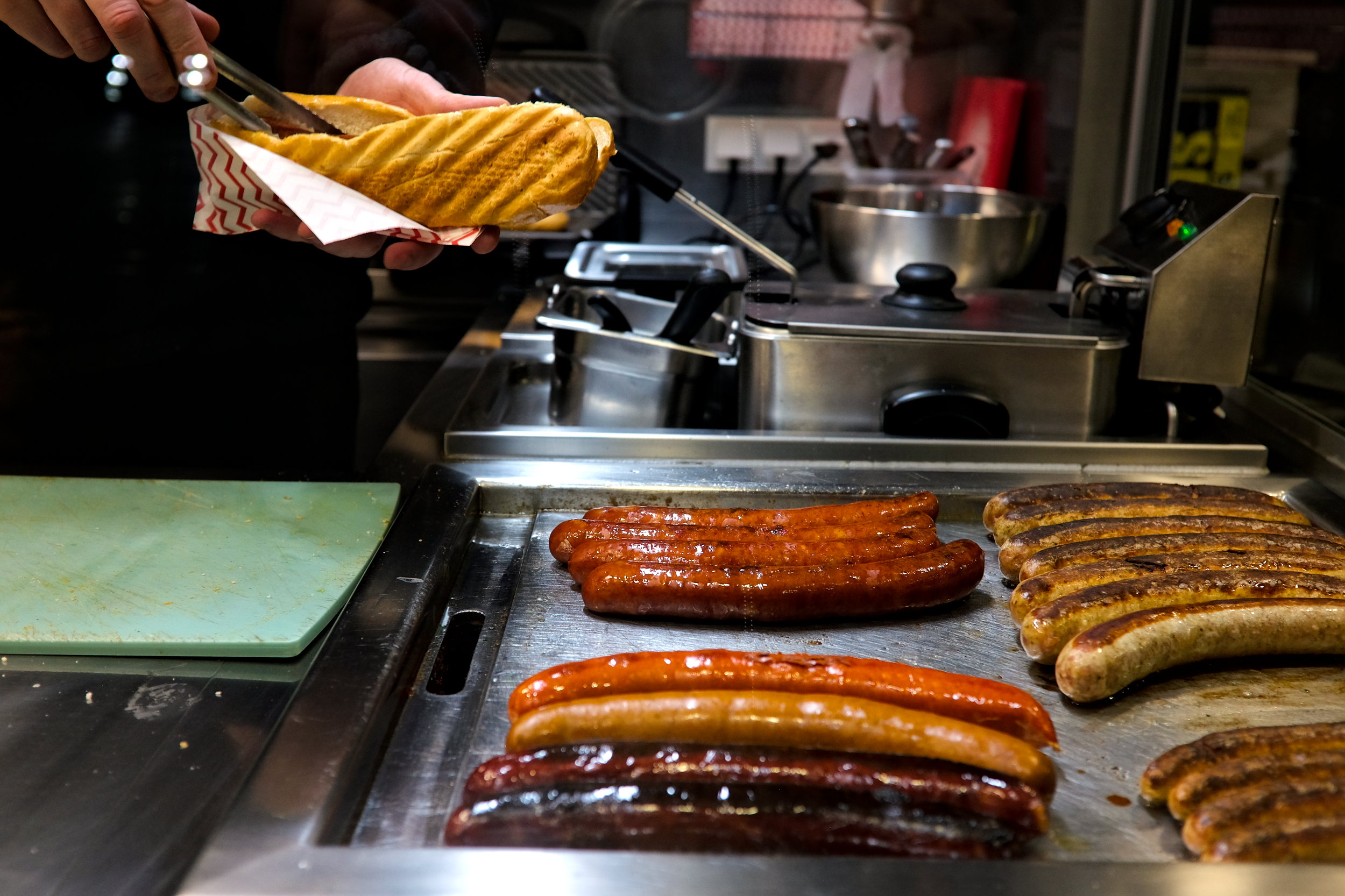 A cook places a sausage in a roll