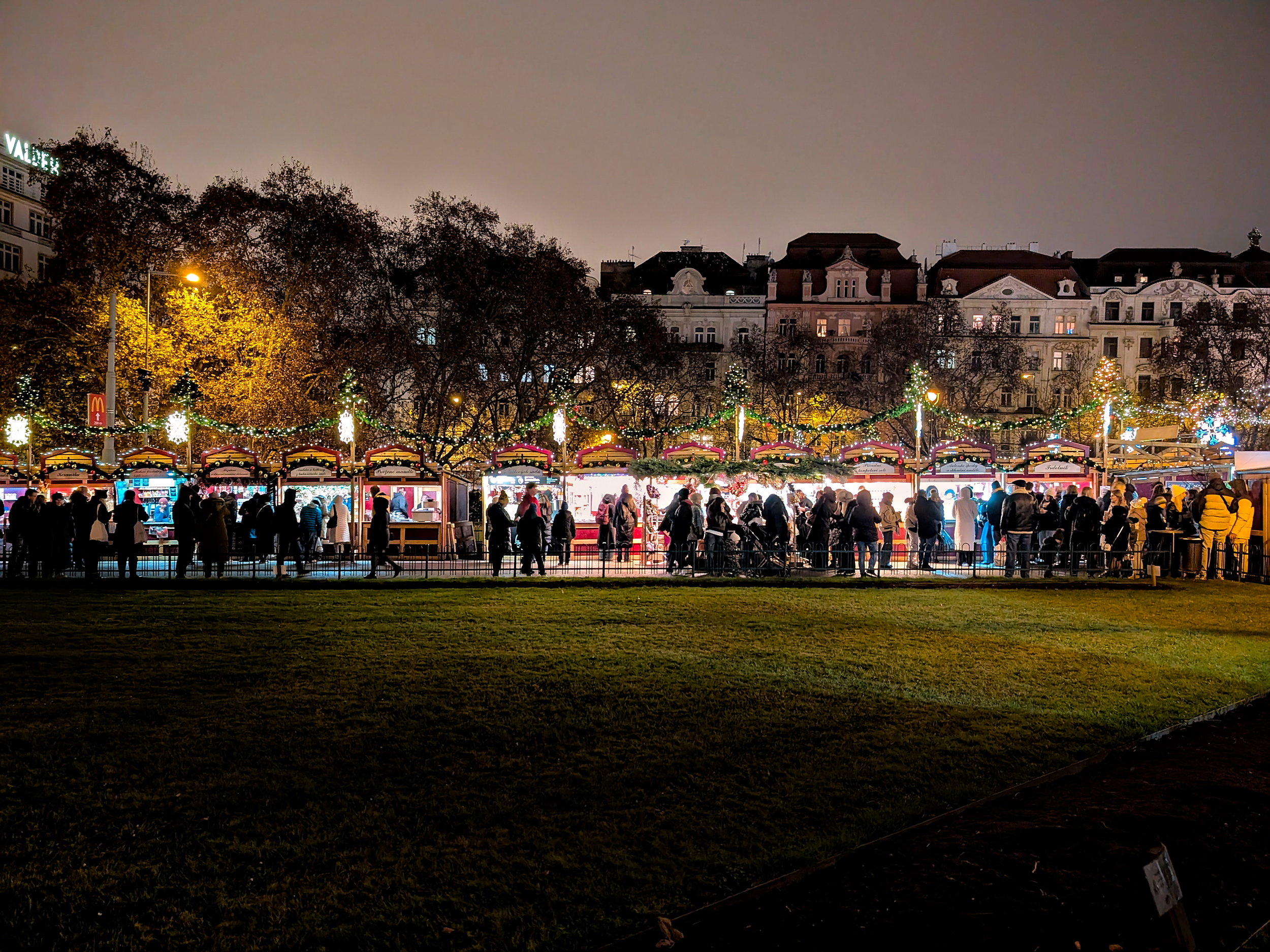 Families stroll rows of vendors at a Christmas market in Prague