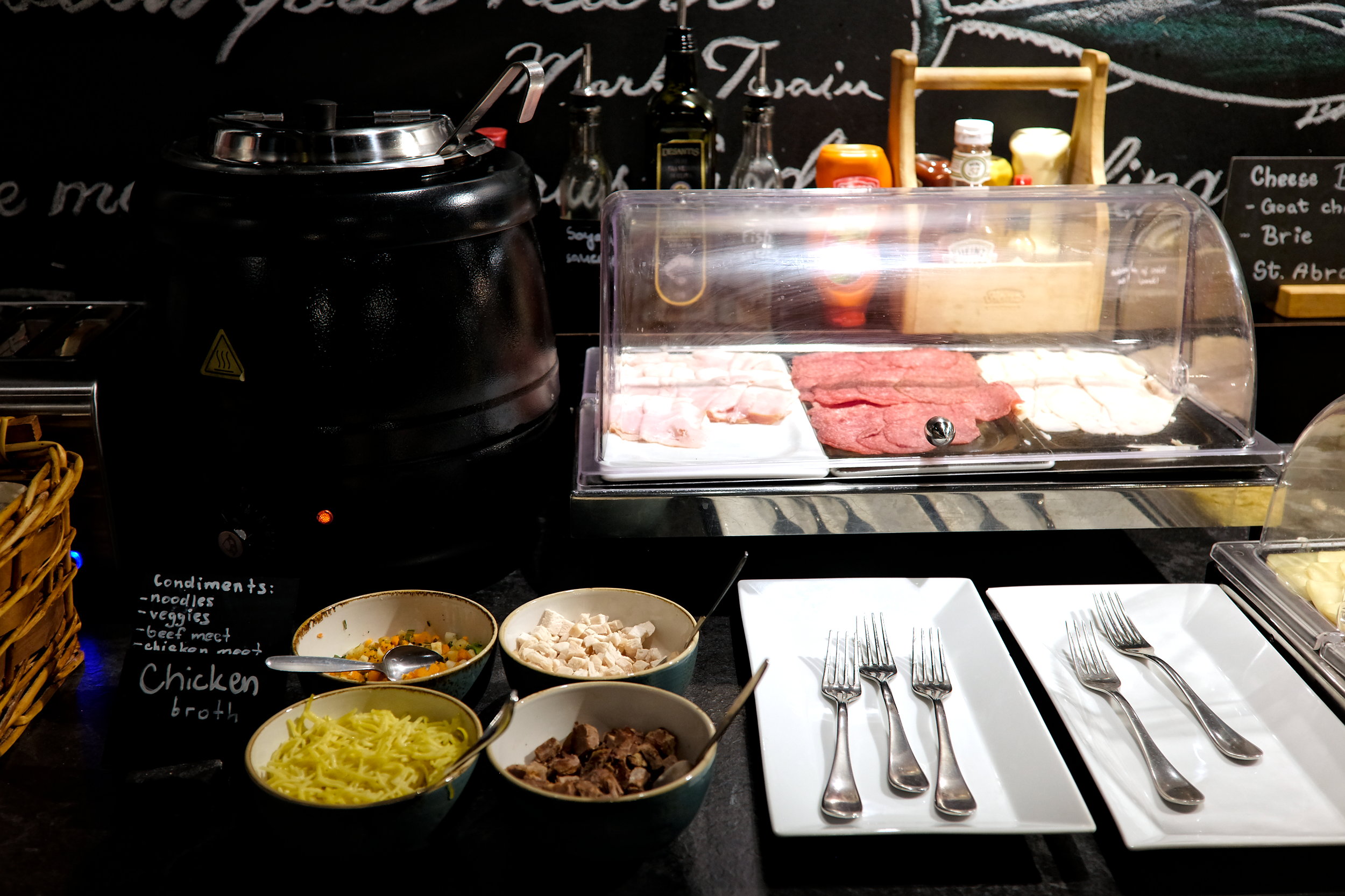 Chicken broth and toppings alongside a case of deli meats