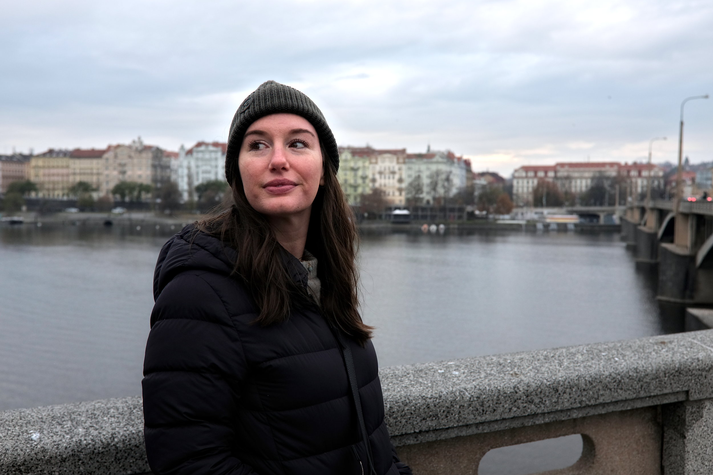 Alyssa wears a grey sweater, green beanie, and puffer coat